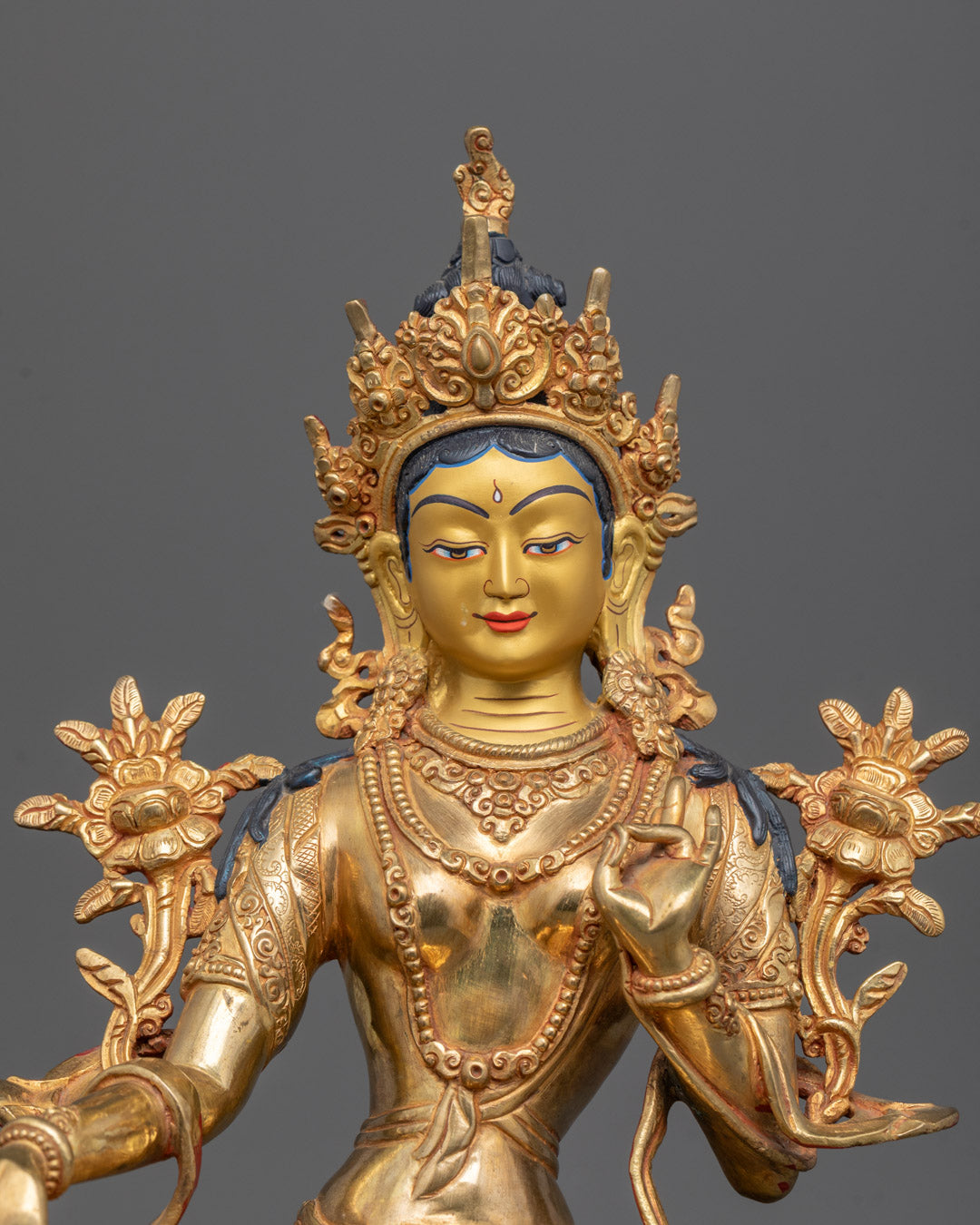 Close-up of Green Tara’s blue utpala flower and detailed 24K gold-gilded face