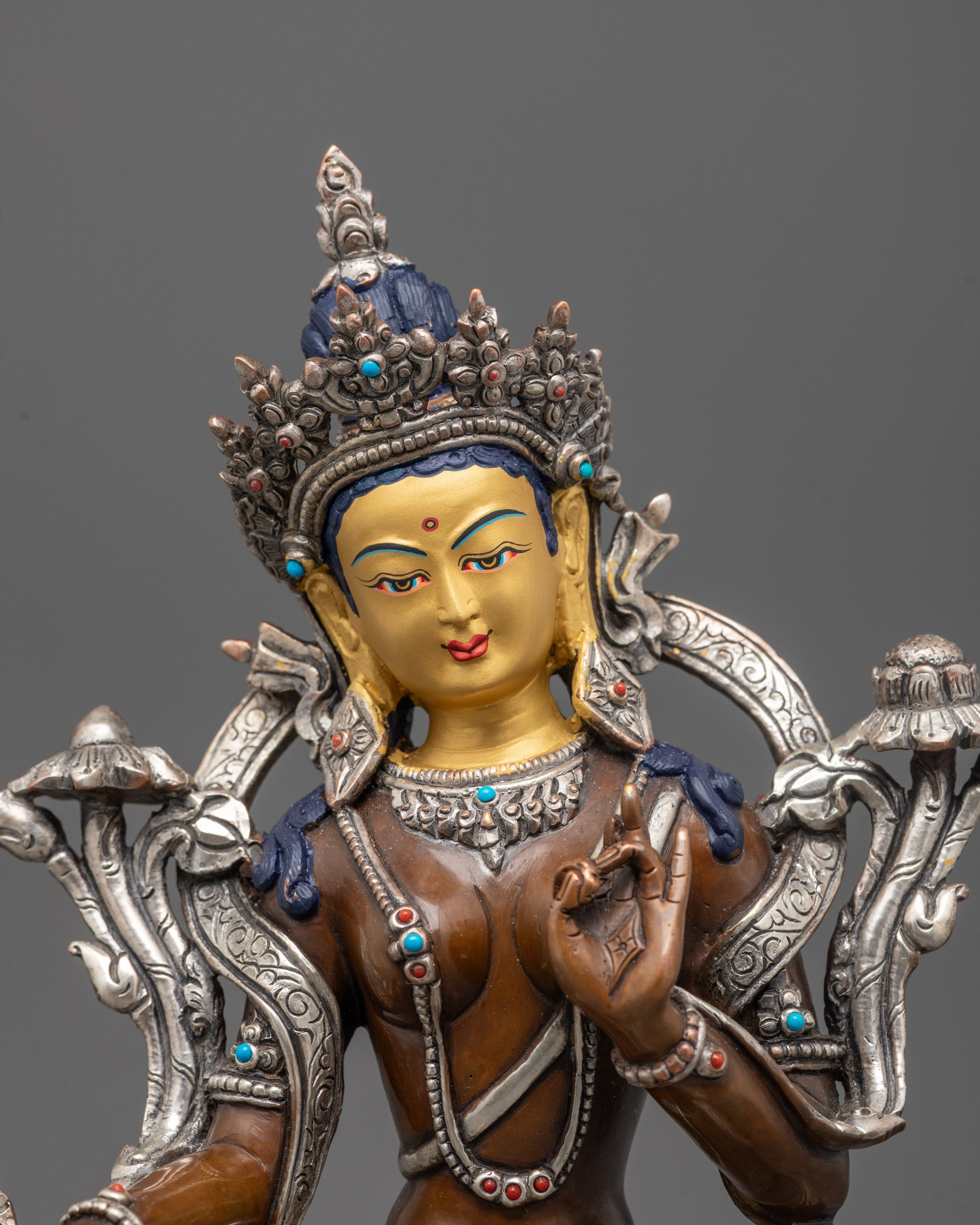Close-up of Green Tara’s gold-gilded face and silver-plated utpala flower details.