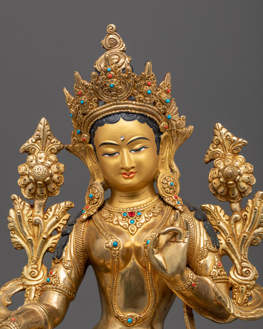 Close-up of Green Tara’s serene expression and detailed gold-plated robes