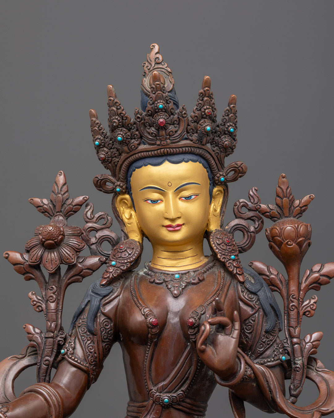 Close-up of Green Tara's serene expression with gold detailing
