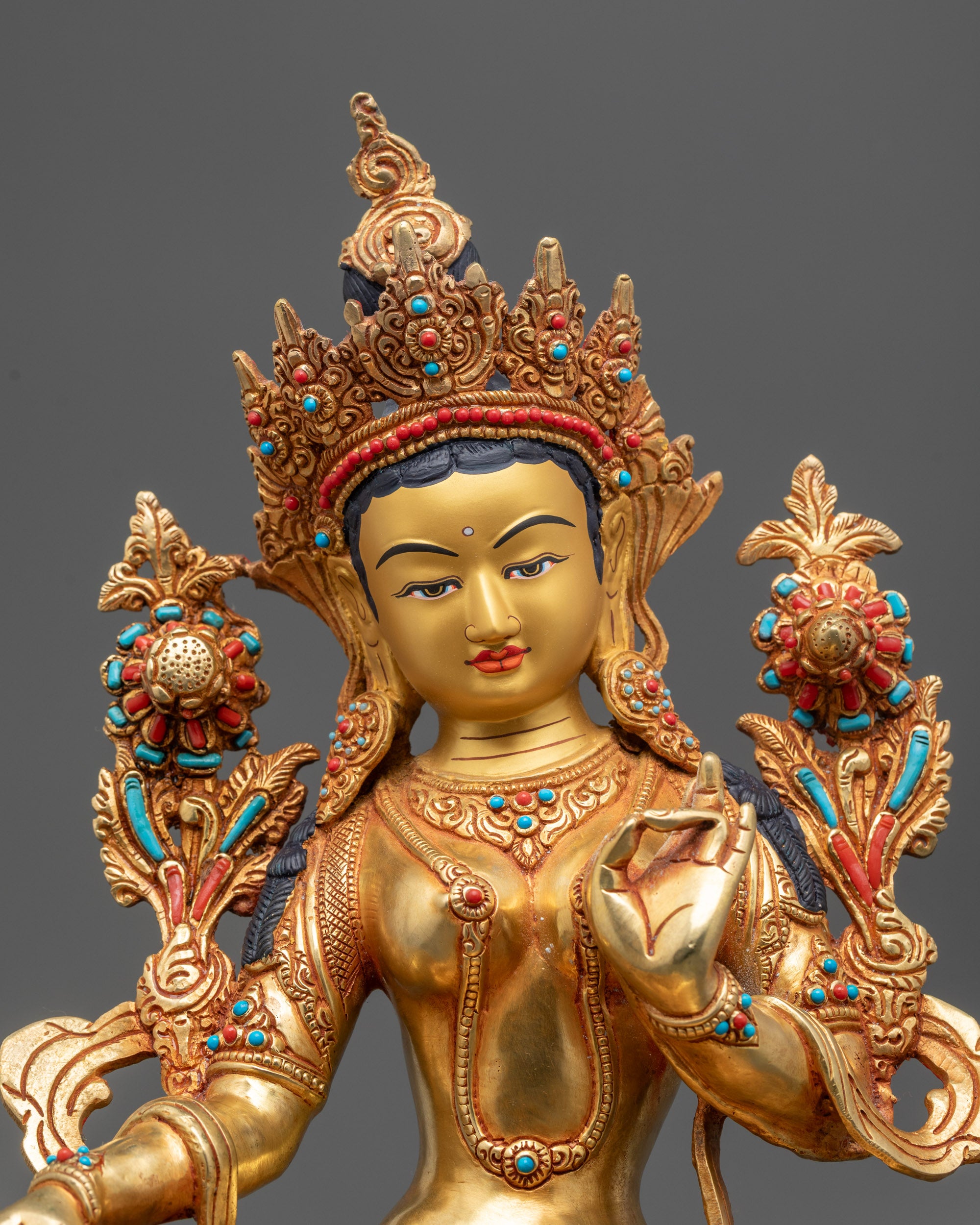 Close-up of Green Tara's serene face and five-jeweled crown with intricate details.