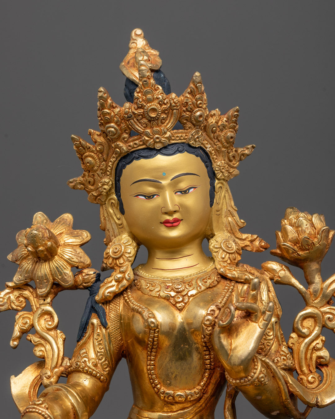 Close-up of Green Tara’s serene face and intricate gold detailing on robes