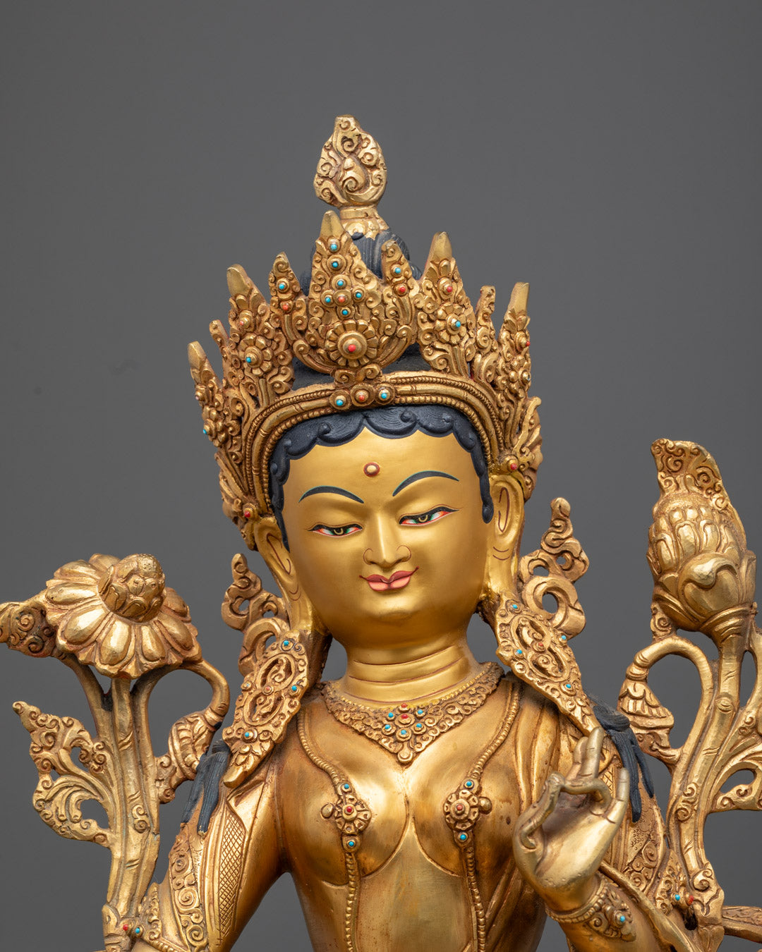 Close-up of Green Tara’s serene face and lotus seat on a traditional Nepalese gold-gilded statue adorned with acrylic colors.