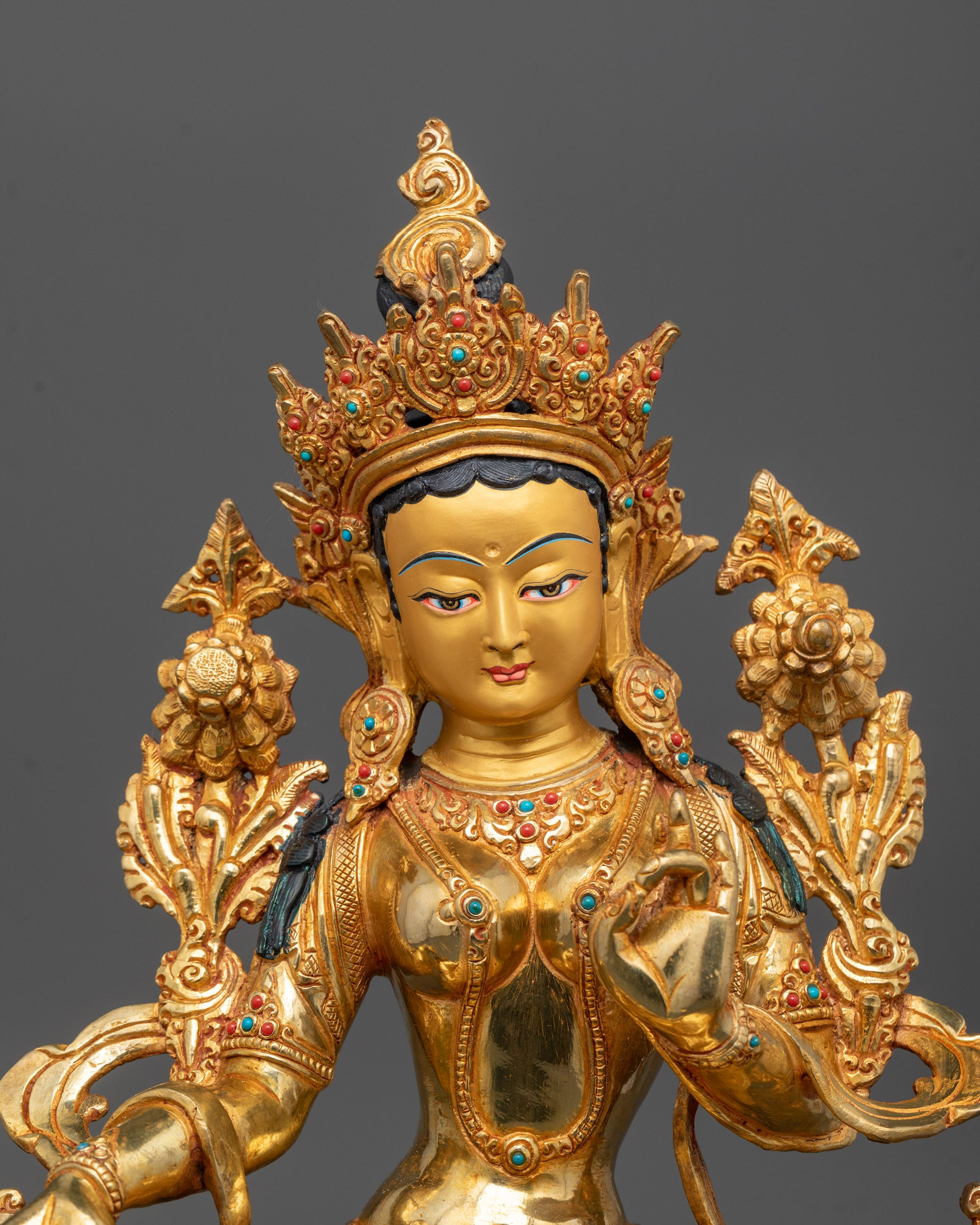 Close-up of Green Tara's serene face with 24k gold gilding and expressive hand