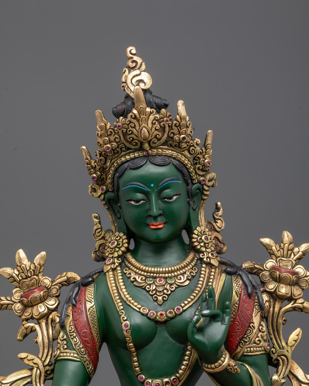 Close-up of Green Tara’s serene gold-gilded face, symbolizing compassion and protection