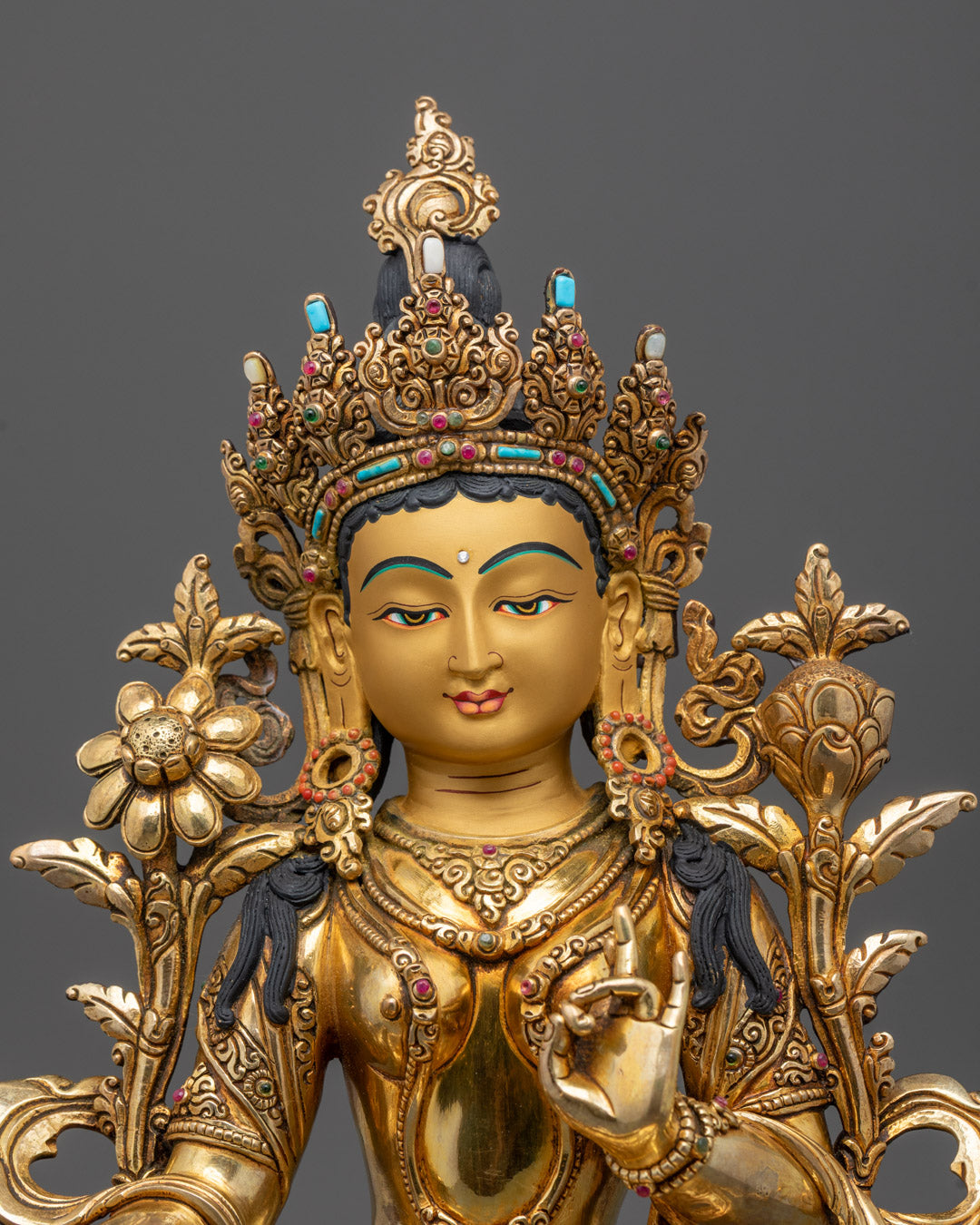 Close-up of Green Tara statue’s gold-gilded face and intricate crown carvings, spiritual art