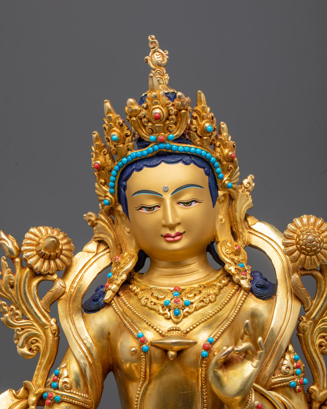 Green Tara statue’s gold-gilded face with vibrant acrylic paint details