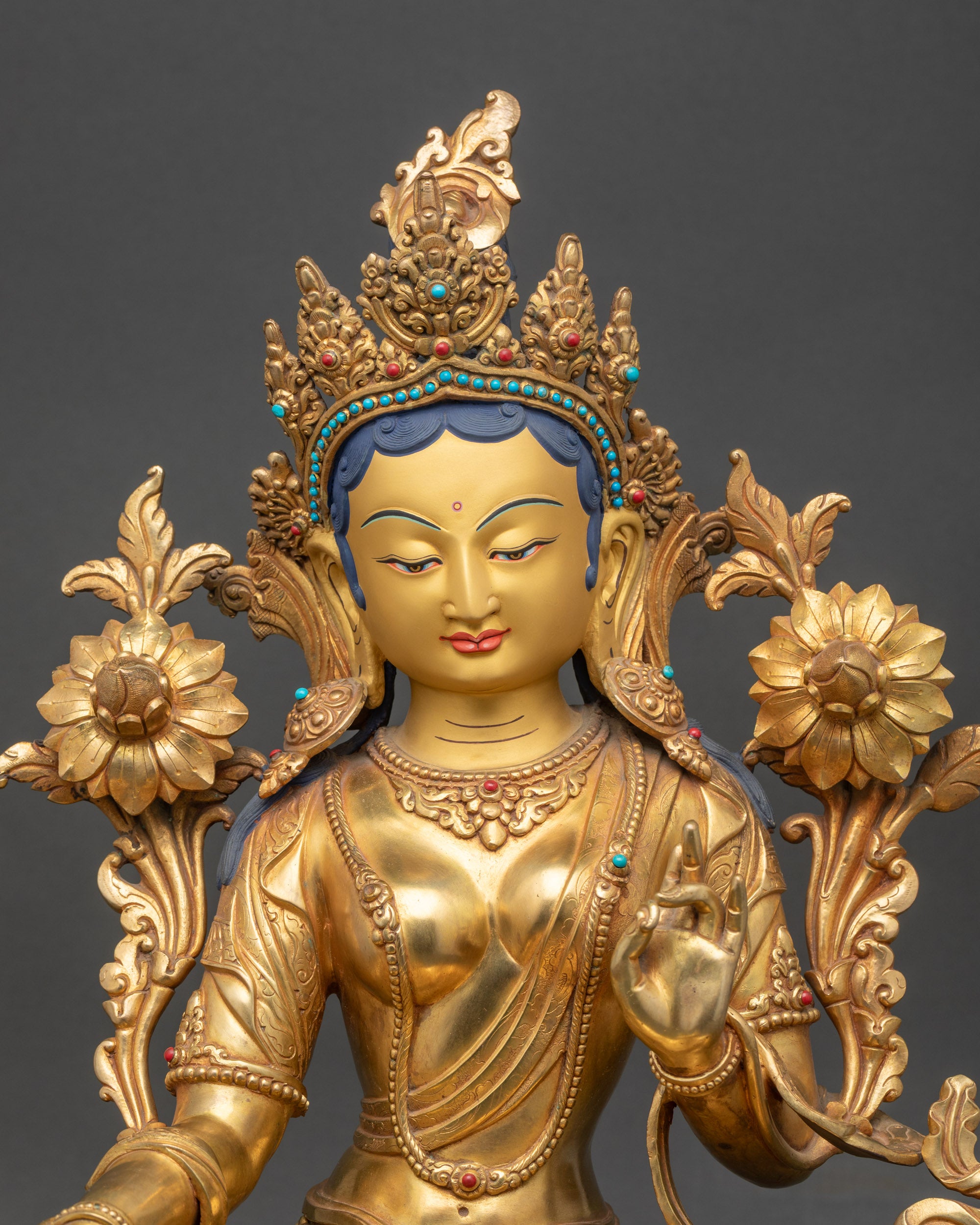 Close-up of Green Tara statue’s serene gold-painted face and five-jeweled crown