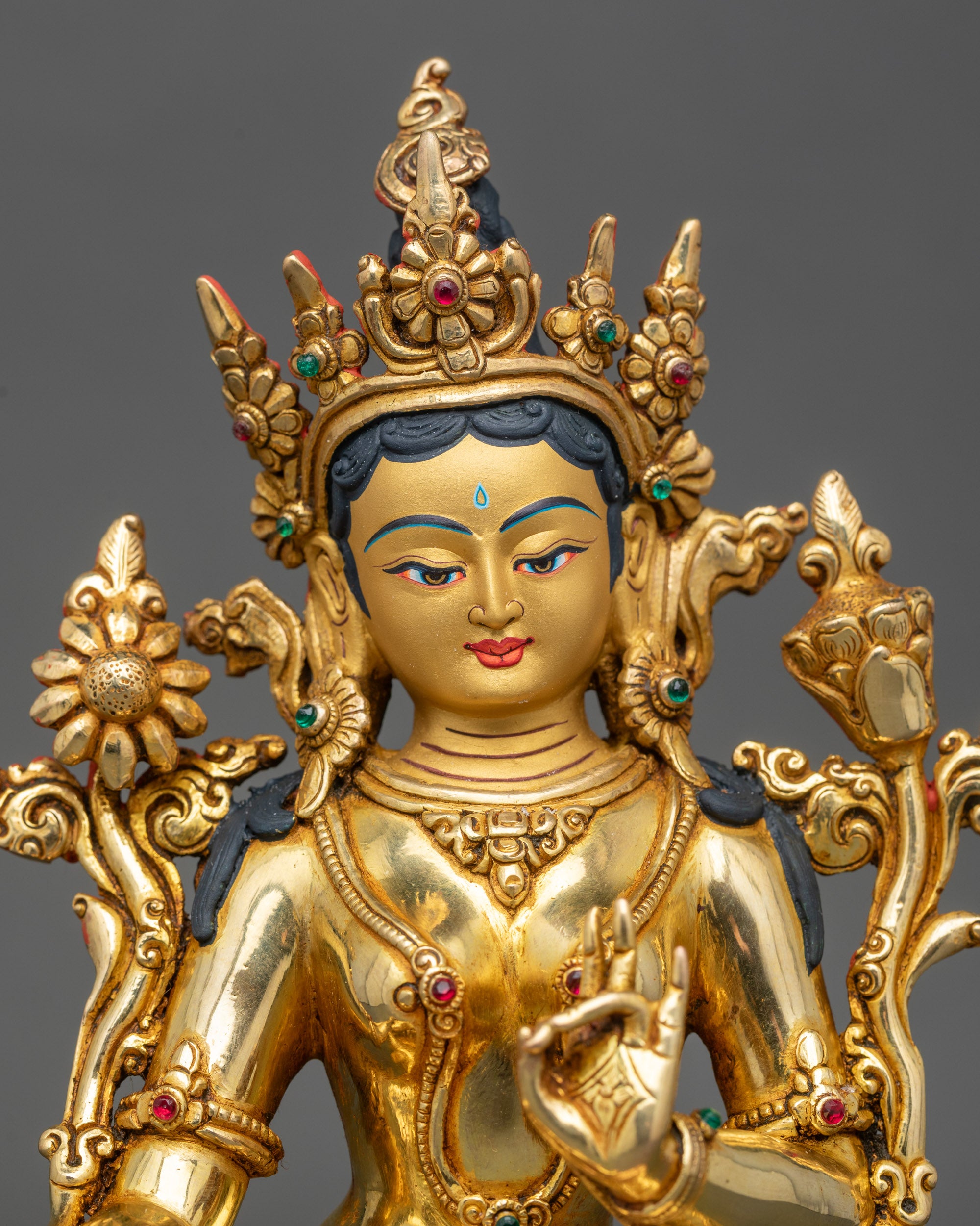Close-up of Green Tara statue showing detailed gold-painted face and utpala flowers