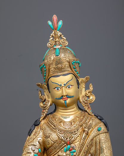 Close-up of Guru Rinpoche holding vajra, skull cup with vase, and khaṭvāṅga trident with three kapalas, showcasing fine lost wax craftsmanship