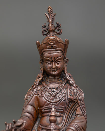 Close-up of Guru Rinpoche’s face with lotus hat, sun and moon symbols, vajra, and vulture feather