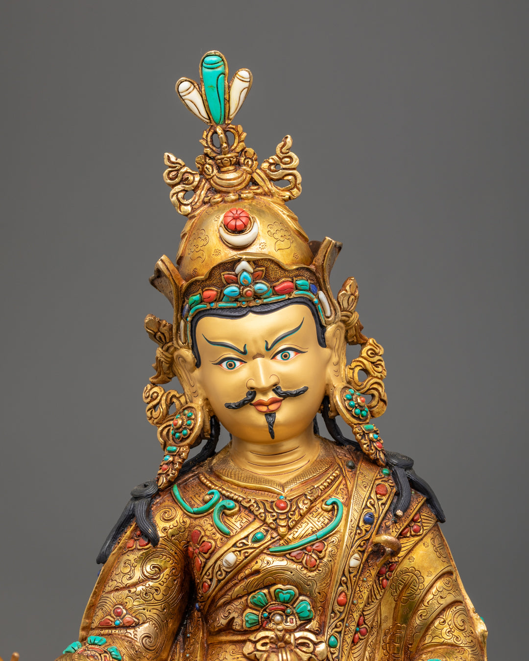Close-up of Guru Rinpoche’s gold-gilded face and ornate crown adorned with acrylic colors and gemstones