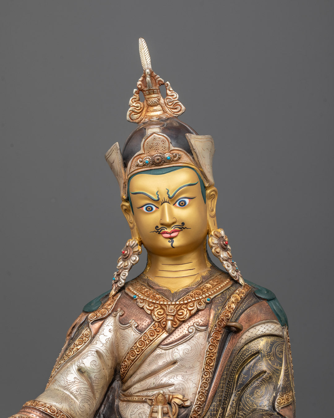 Close-up of Guru Rinpoche’s jewel-encrusted crown, vajra, skull cup, and sacred Tripitaka robes