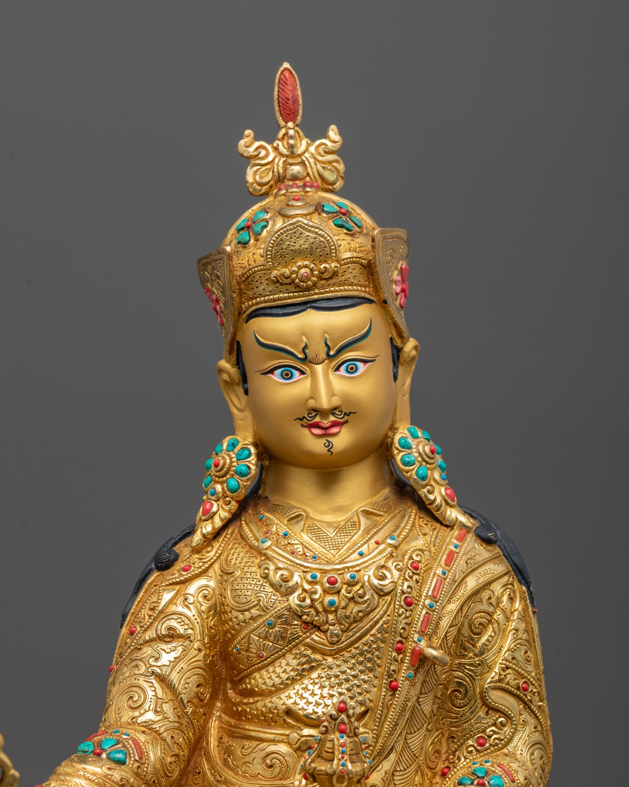 Close-up of Guru Rinpoche’s semi-wrathful face with detailed gold gilding and intricate craftsmanship