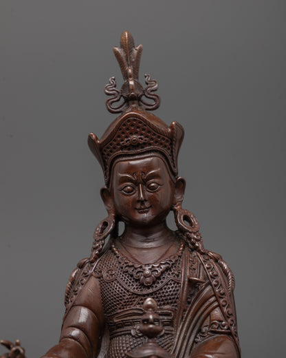 Close-up of Padmasambhava statue showing oxidized copper face and khatvanga trident
