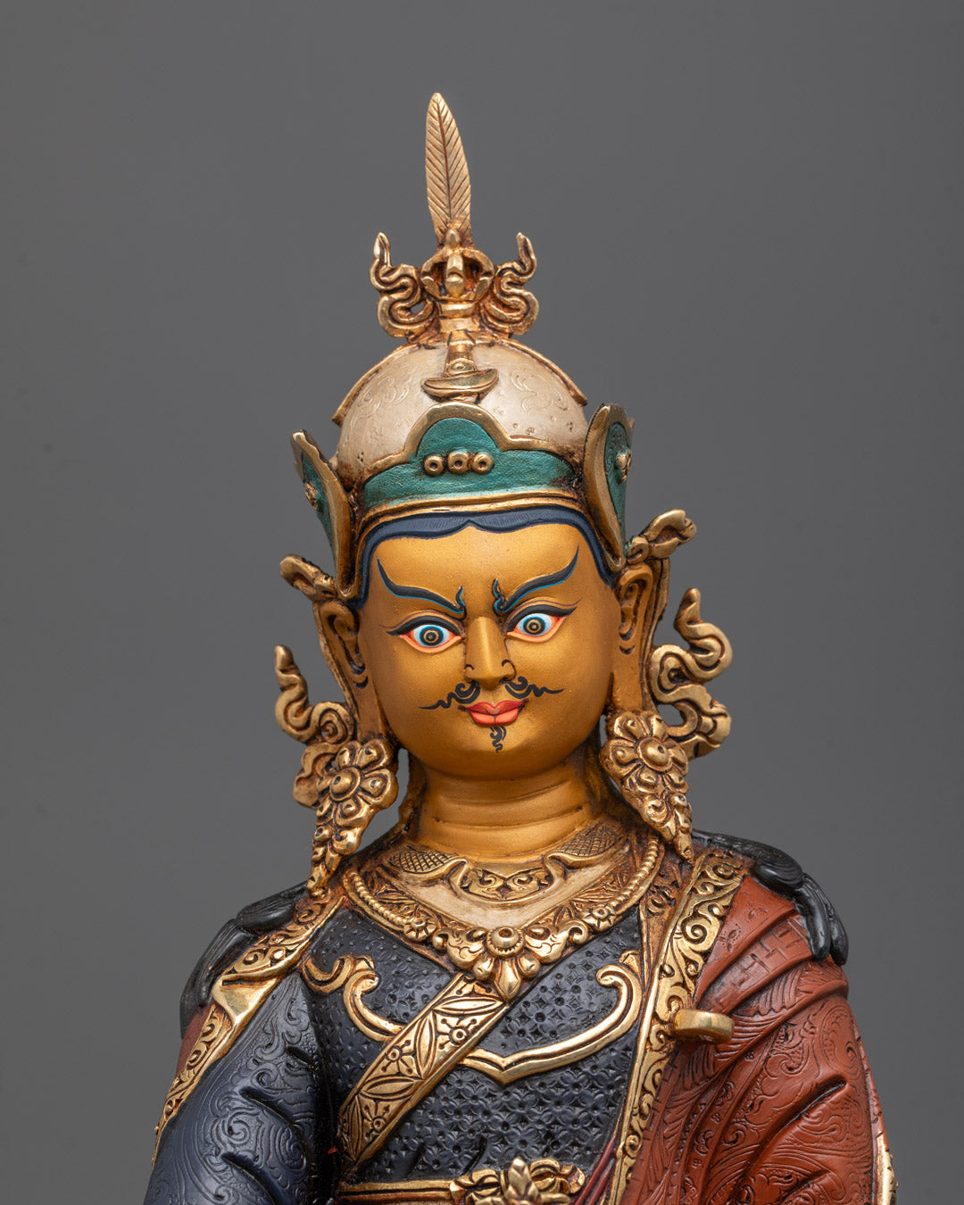Close-up of Guru Rinpoche statue’s gold-gilded face showcasing detailed craftsmanship and acrylic colors