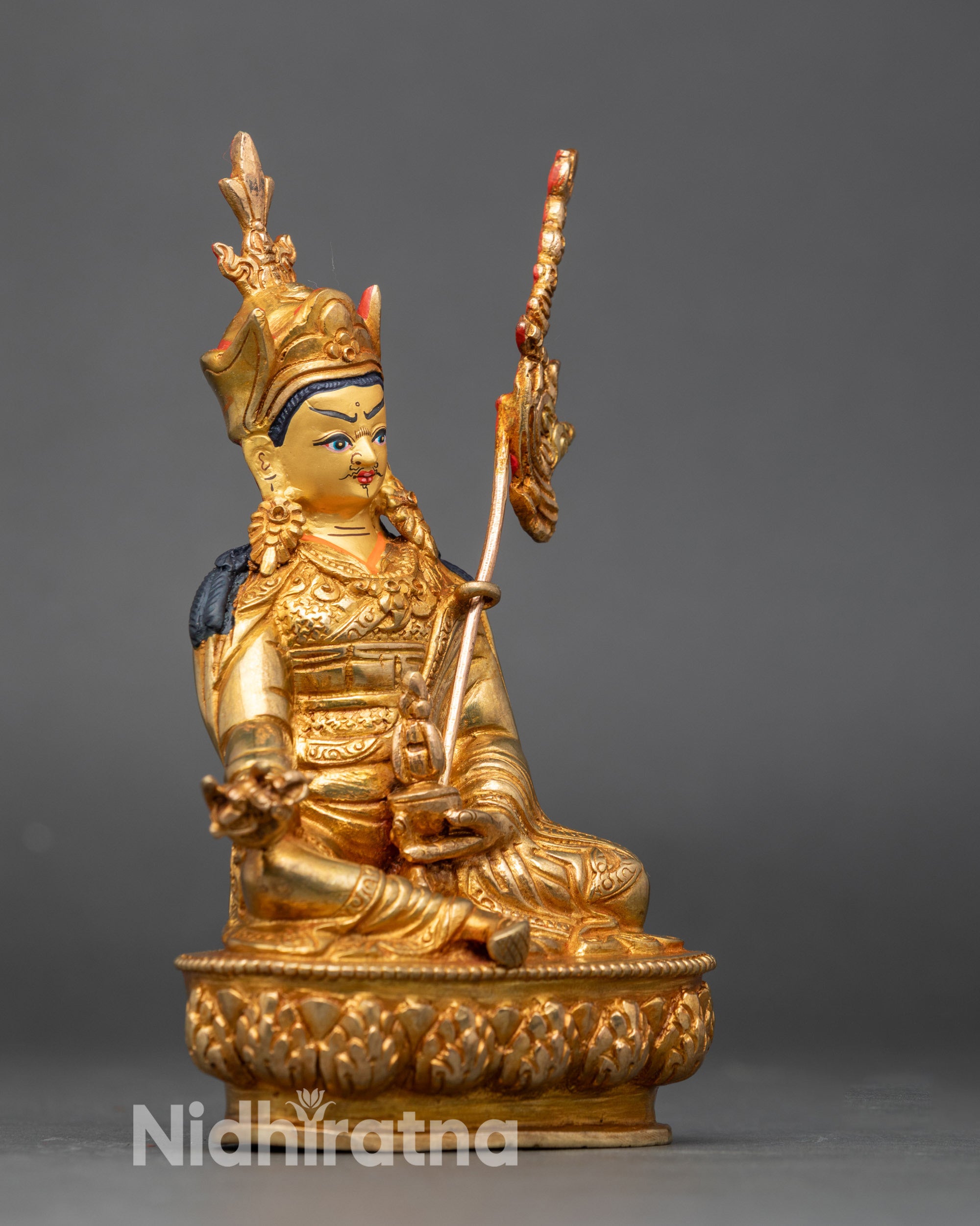 Close-up of Guru Rinpoche statue showing intricate gold fire-gilded details and polished finish