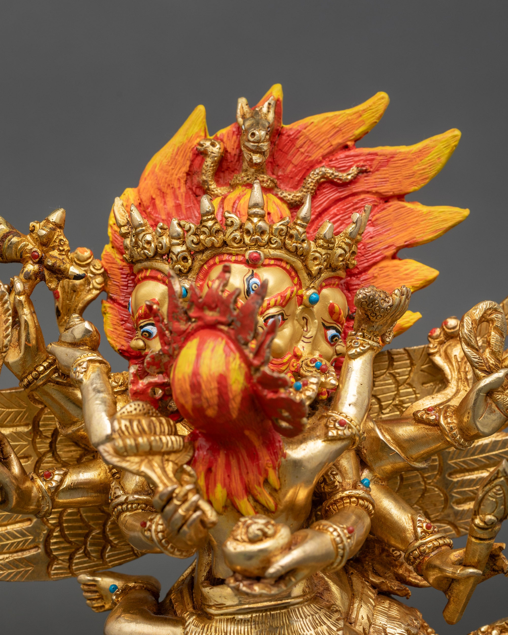 Close-up of Hayagriva gold-painted face with intricate jewelry and carved robe details