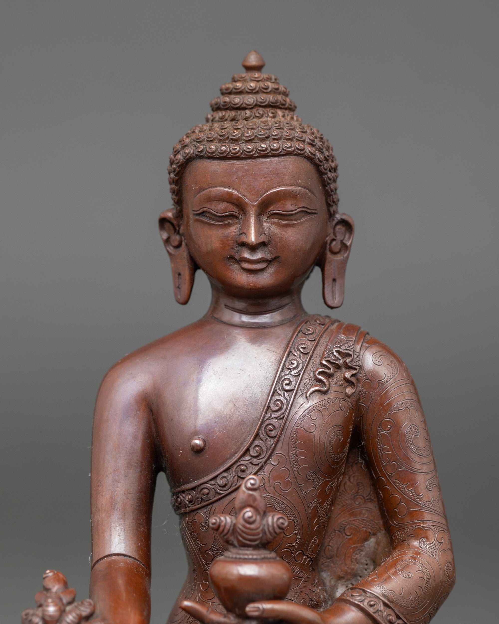 Close-up of Healing Buddha figurine showing bowl of nectar and myrobalan plant