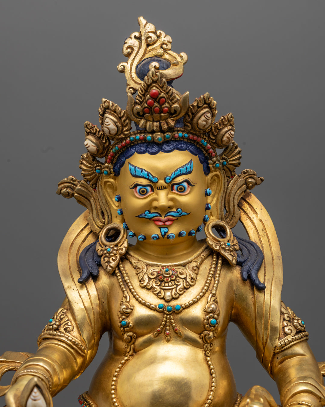 Jambhala statue adorned with semi-precious stones and detailed carvings.