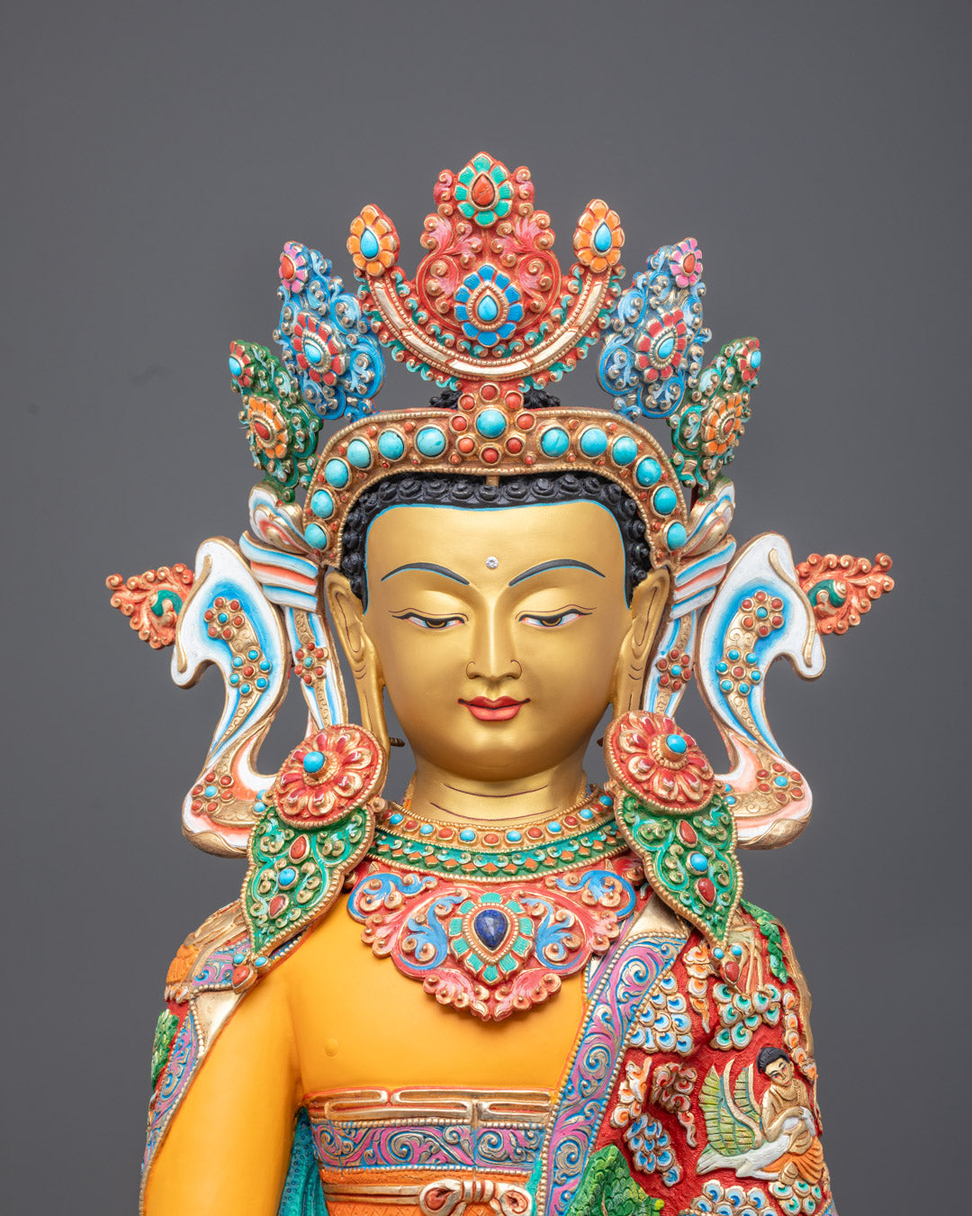 Jowo Rinpoche statue's face, highlighting intricate craftsmanship, gold gilded finish, and vibrant yellow acrylic color accents.