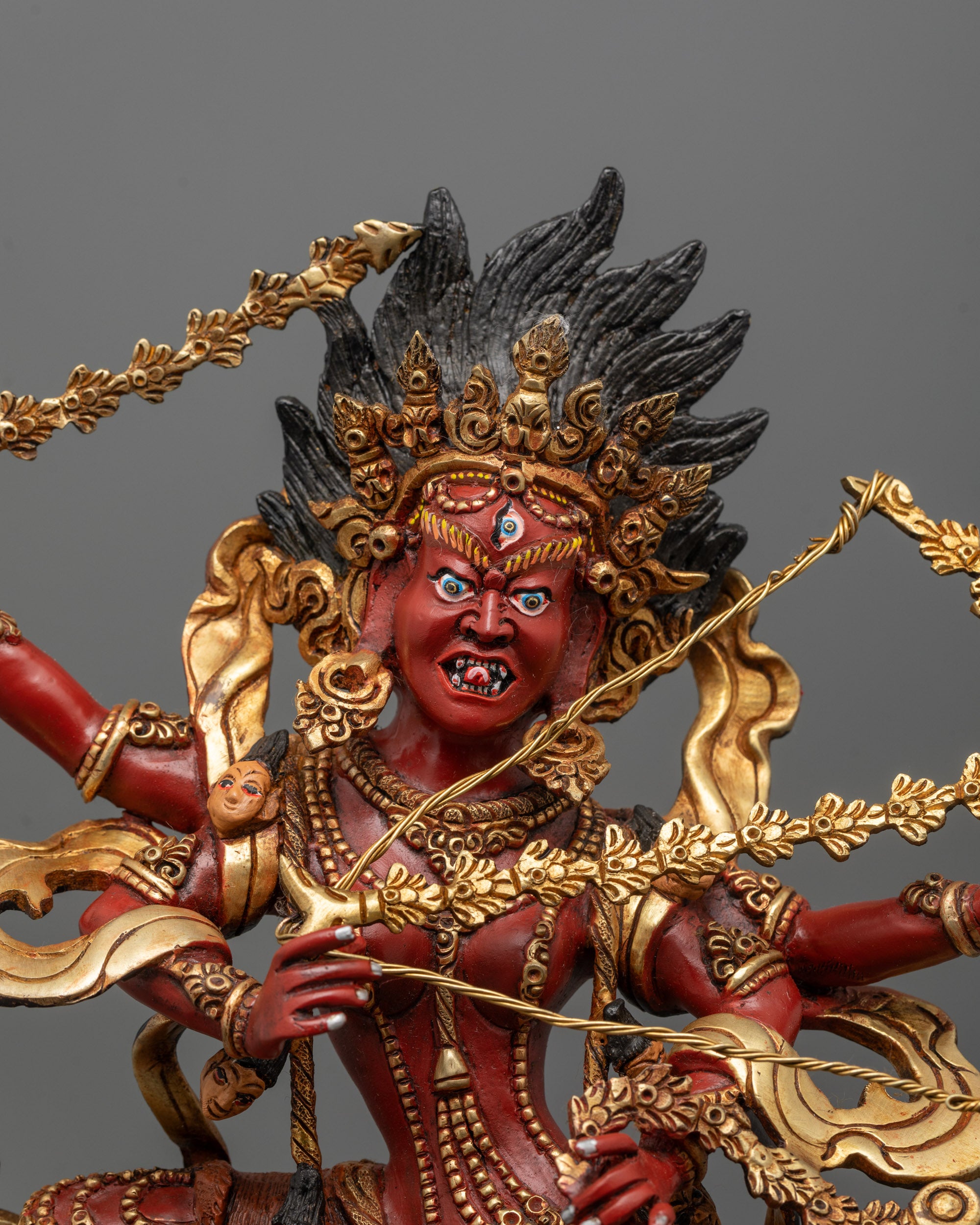 Close-up of Kurukulla’s four arms holding bow, arrow, hook, and lasso in detail