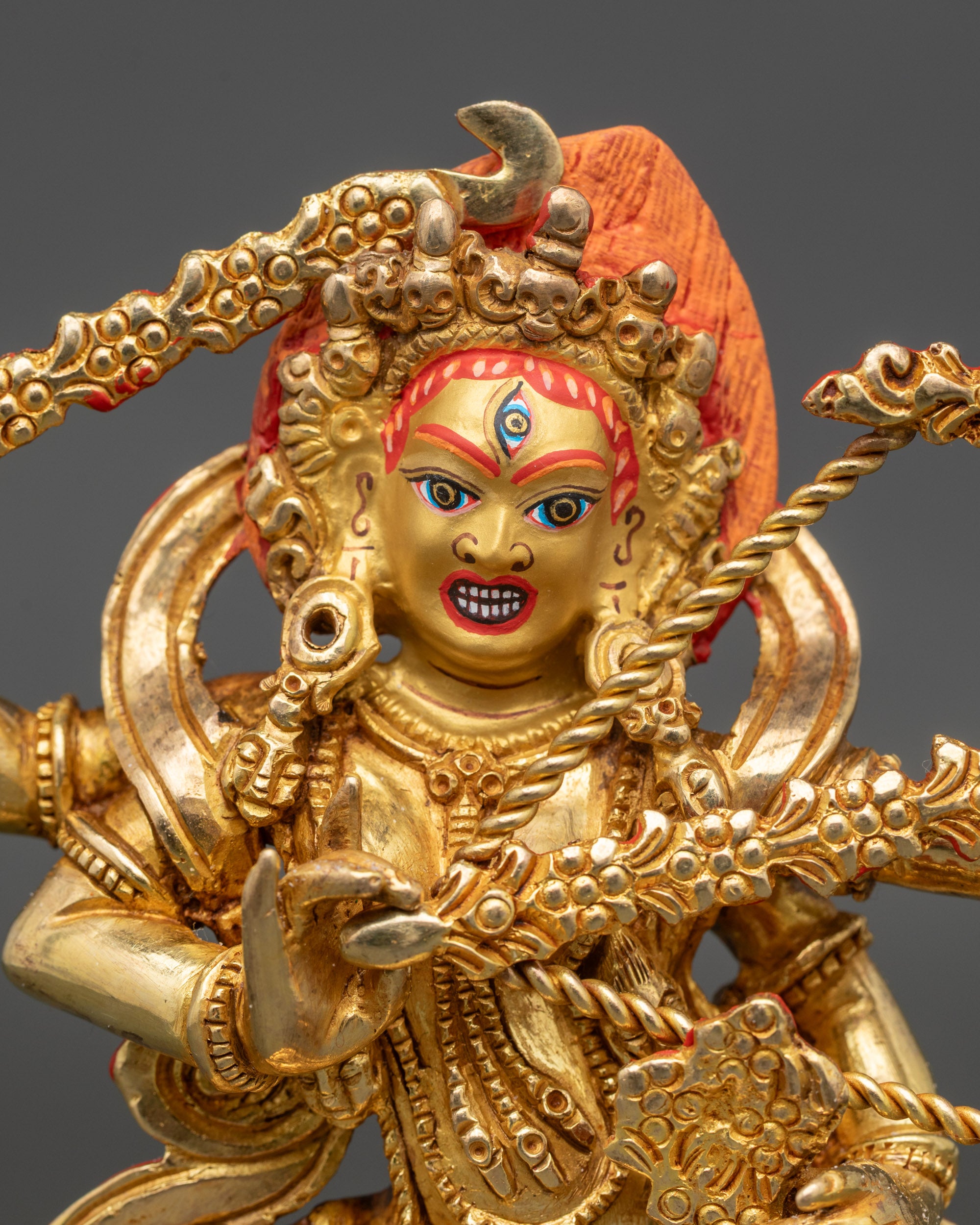 Close-up of Kurukulla statue showing gold-painted face and intricate four-arm details