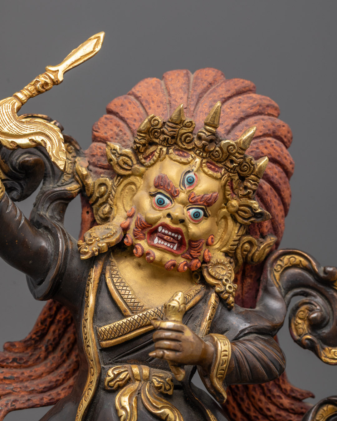 Close-up of Mahakala’s gold-plated face, intricate jewelry, and wrathful expression with halo background
