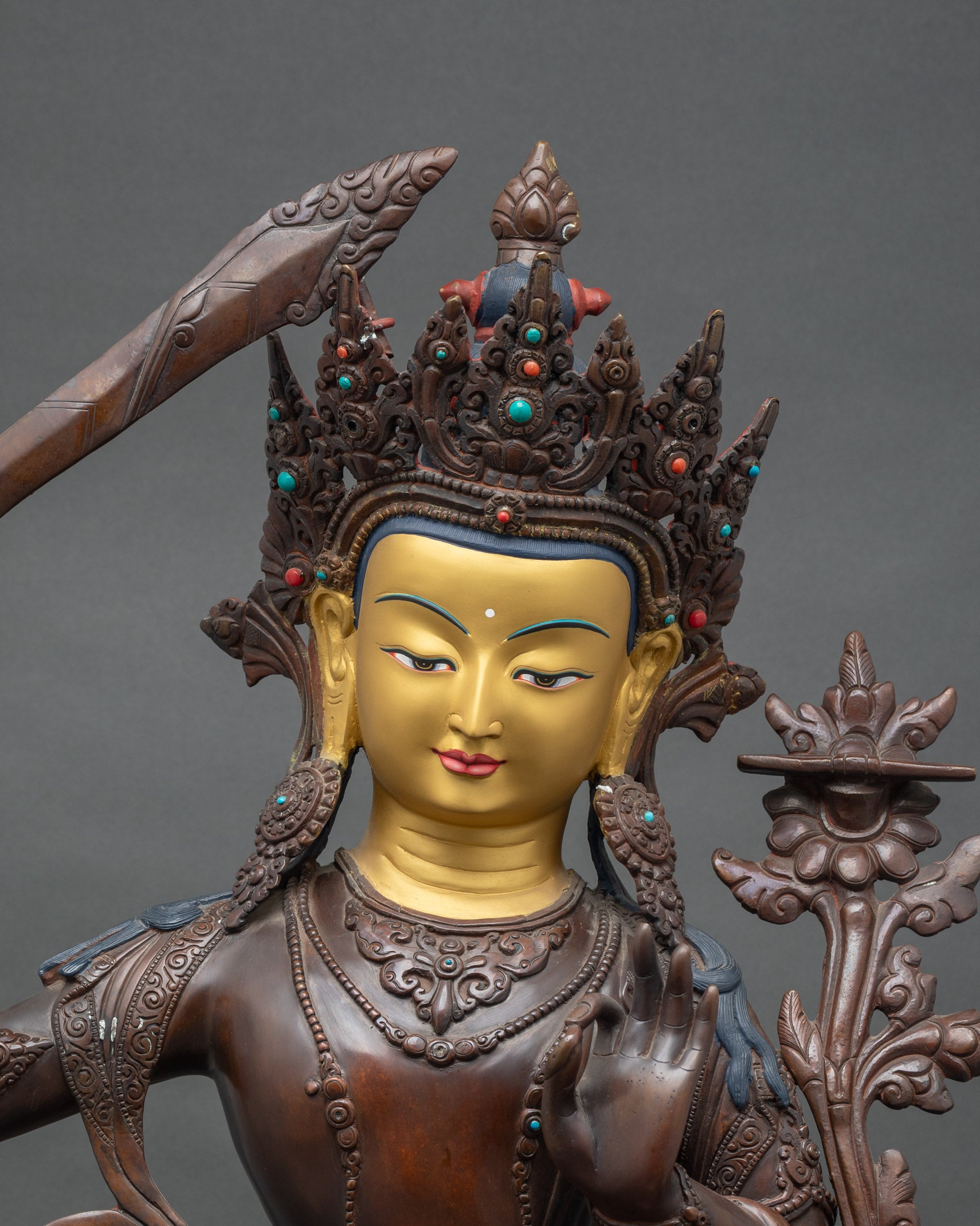 Close-up of Manjushri Bodhisattva sculpture showing flaming sword and lotus scripture