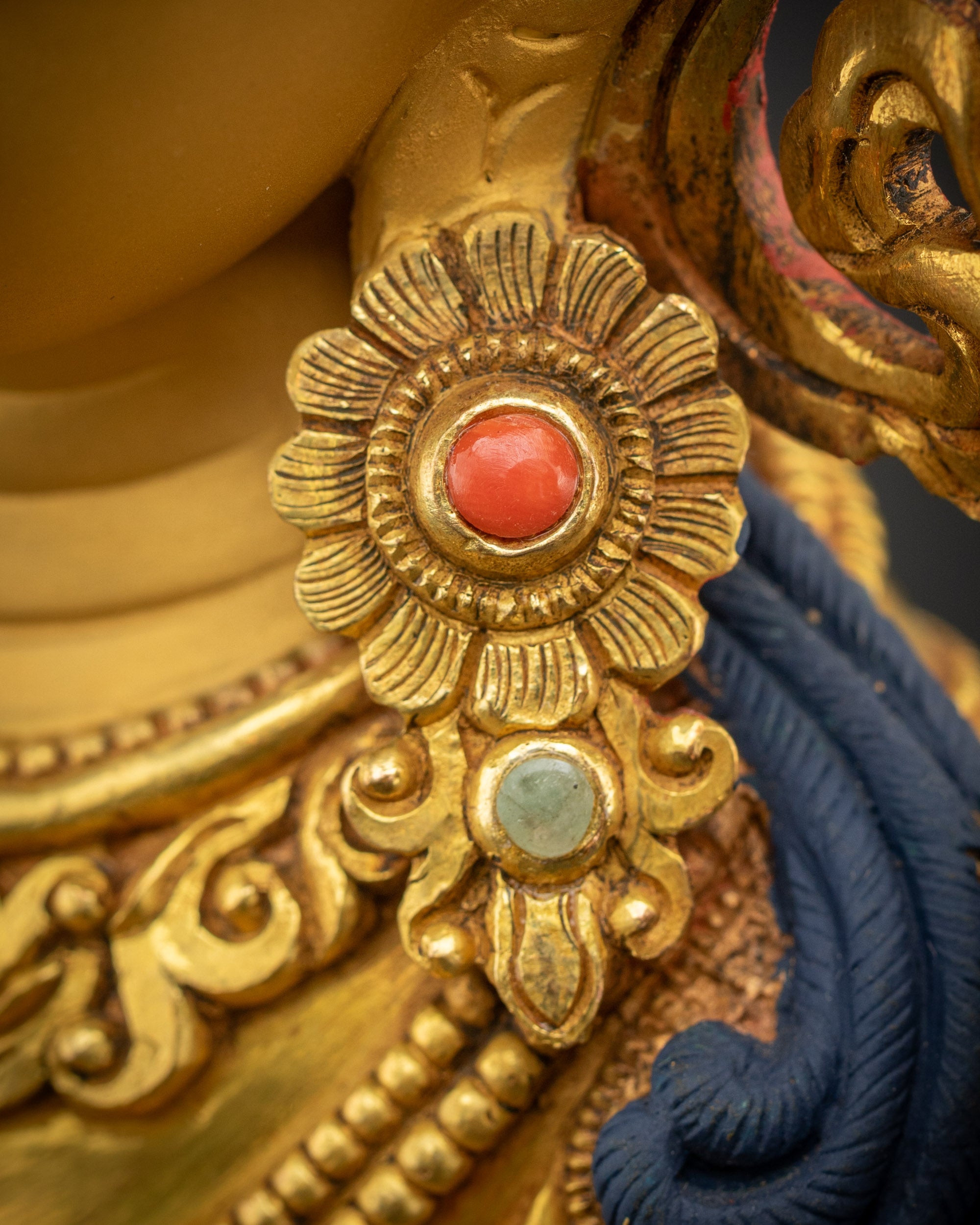 Close-up of Manjushri earrings with intricate gold fire-gilded detailing
