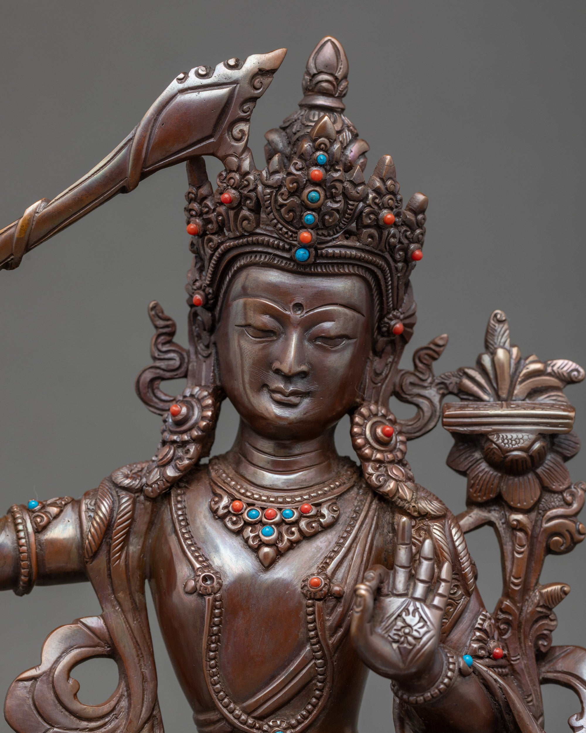 Close-up of Manjushri face, gold-painted details with turquoise and coral stones
