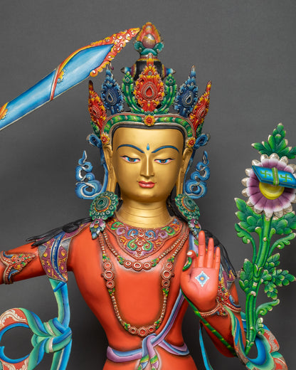 Close-up of Manjushri sculpture showing detailed floral robes and painted copper body