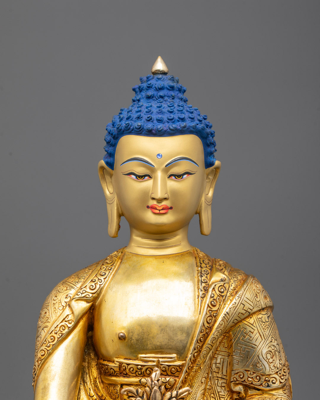 Close-up of Medicine Buddha’s serene gilded face and right hand holding a healing herb