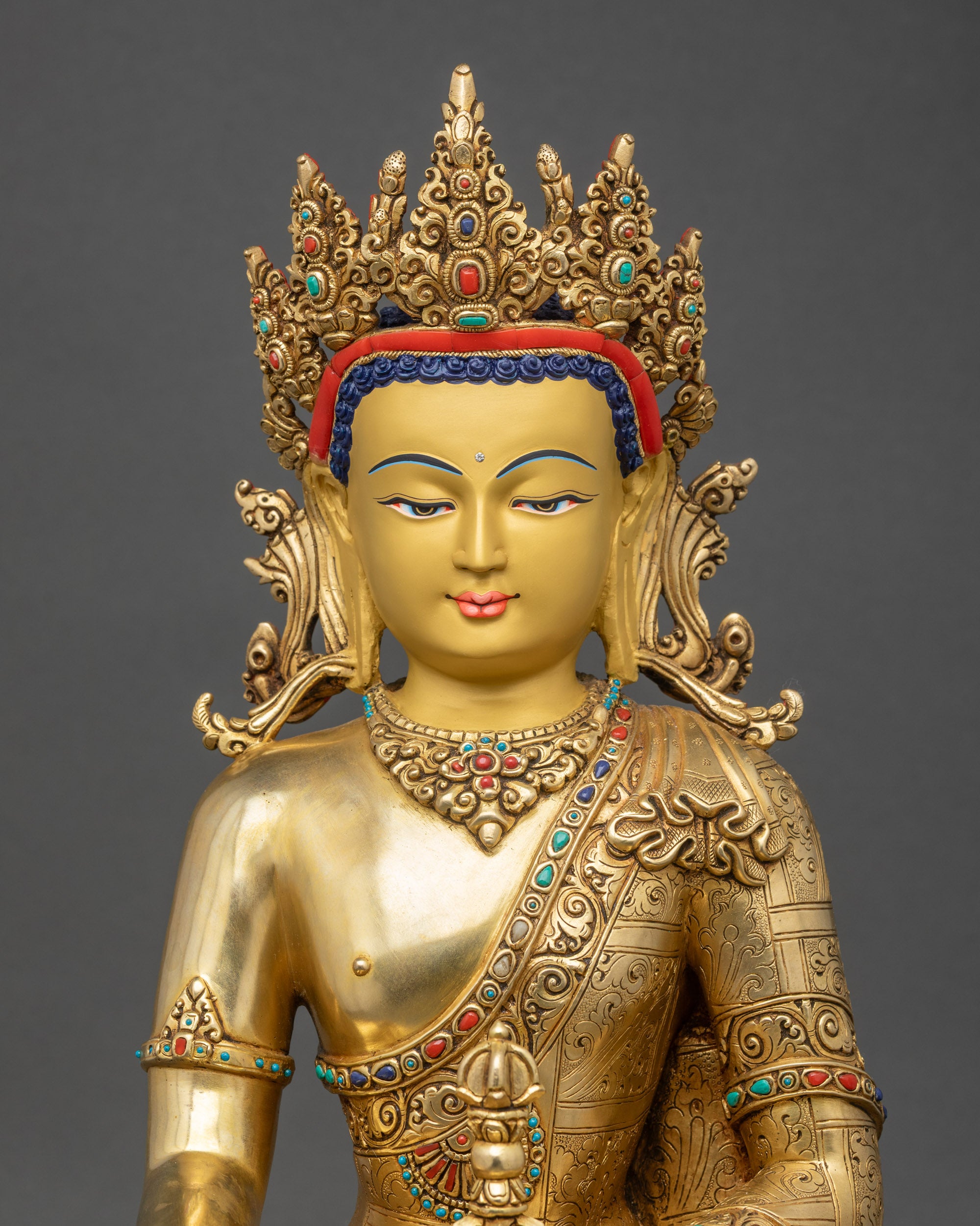 Close-up of Mitrugpa Buddha statue showing serene gold-painted face and intricate monk’s robe.