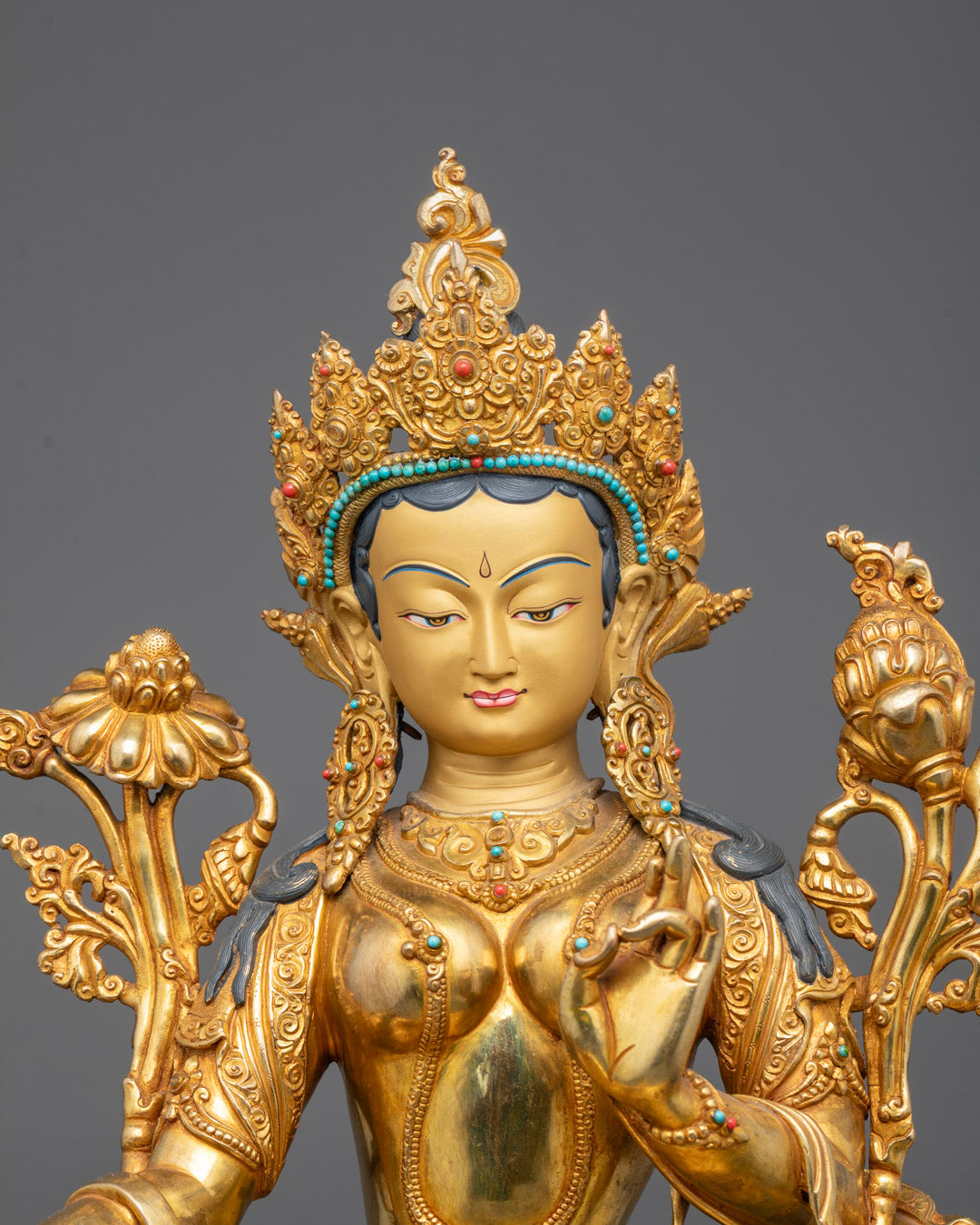 Close-up of Mother Tara’s gold-gilded face with semi-precious stones and vivid paints