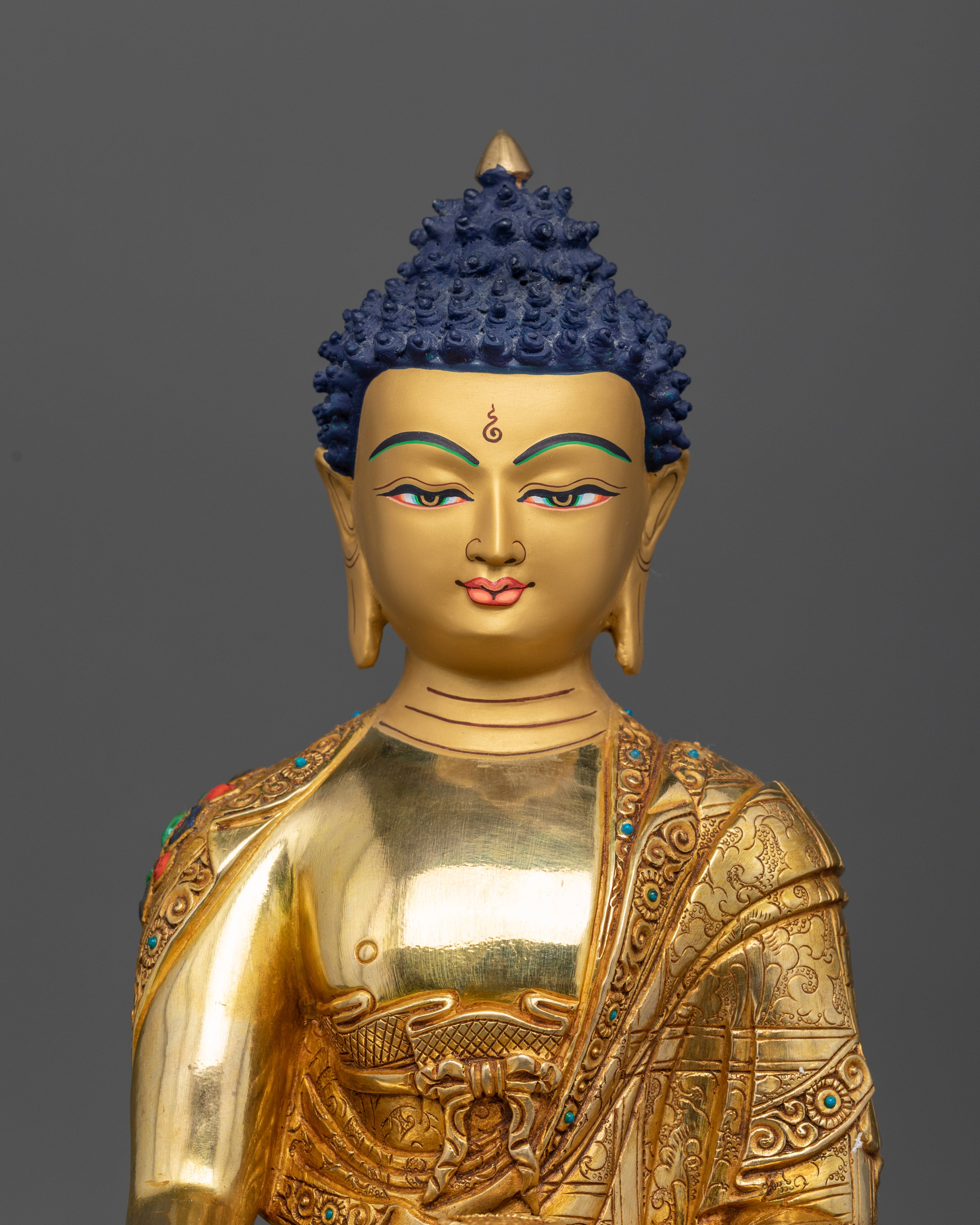 Close-up of Sakyamuni Buddha statue showing detailed monk robe with semi-precious stones