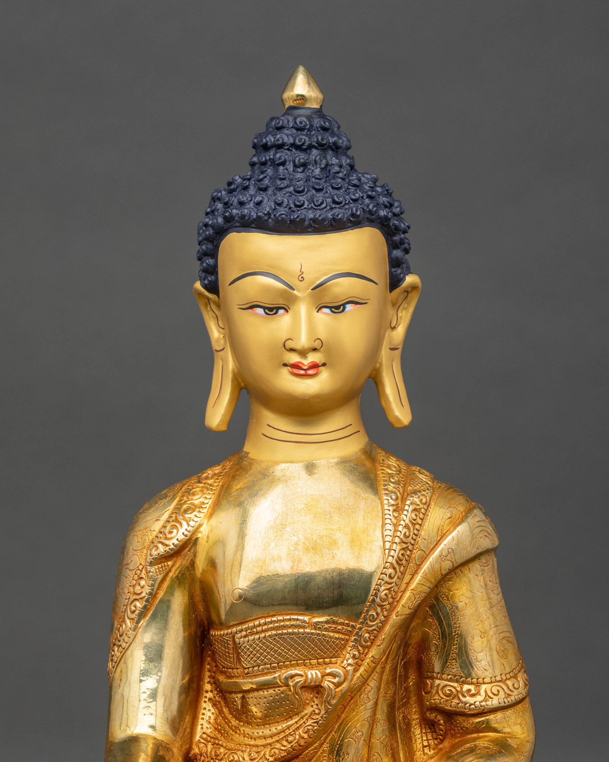 Close-up of Shakyamuni Buddha copper figurine showing intricate robe and lotus base details