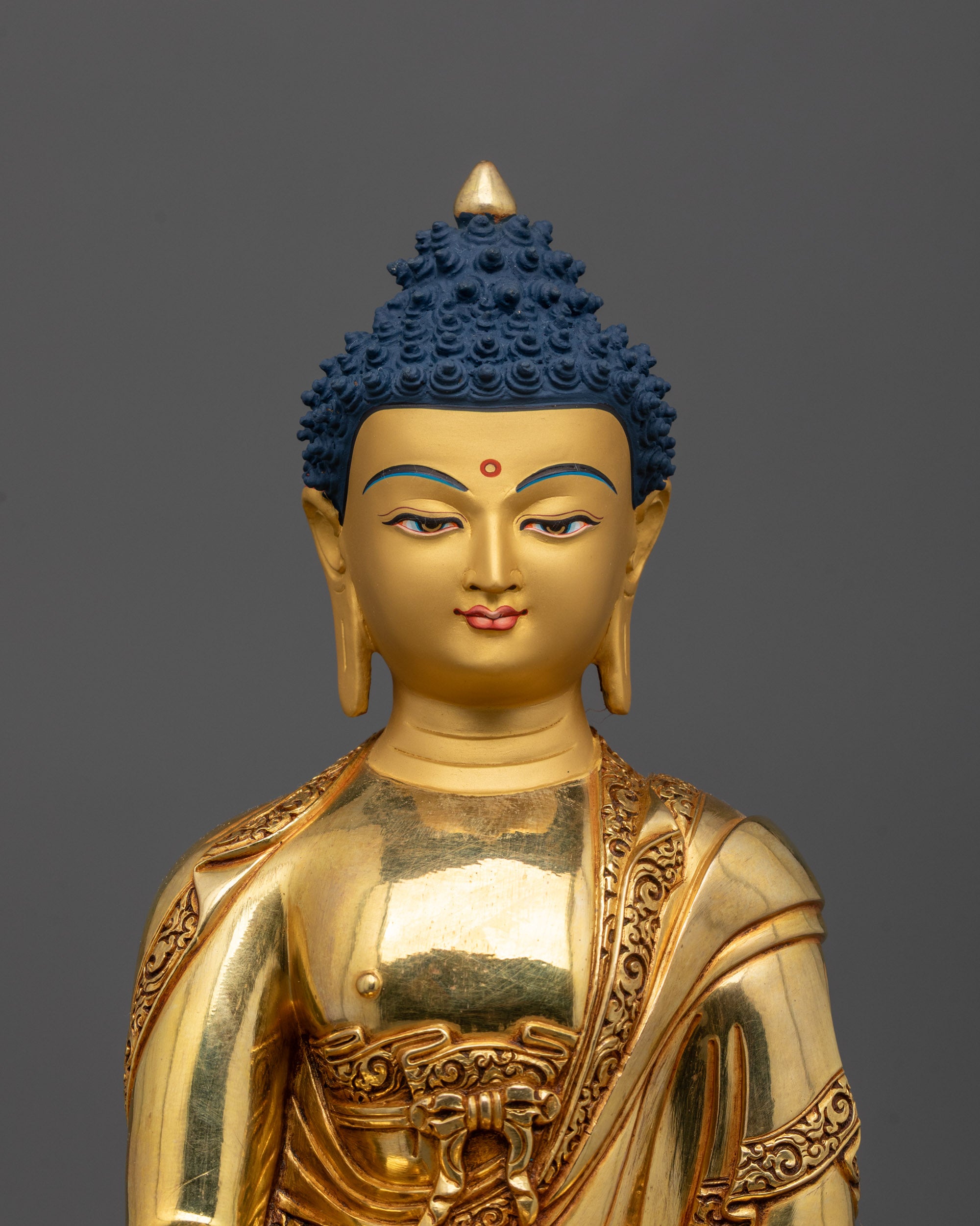 Close-up of Shakyamuni Buddha face with serene expression and intricate 24k gold detailing