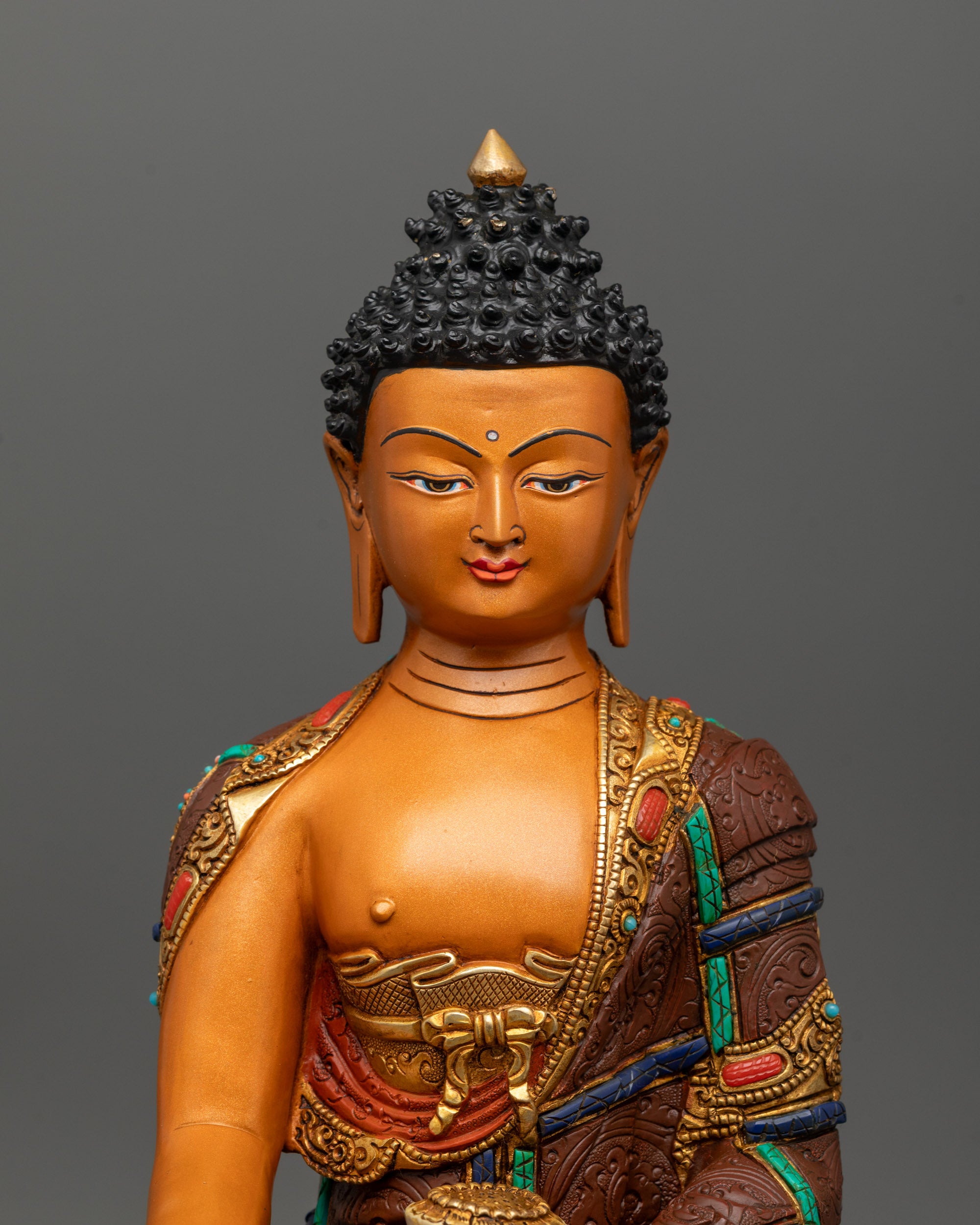 Close-up of Shakyamuni Buddha face with serene expression, intricate copper carving