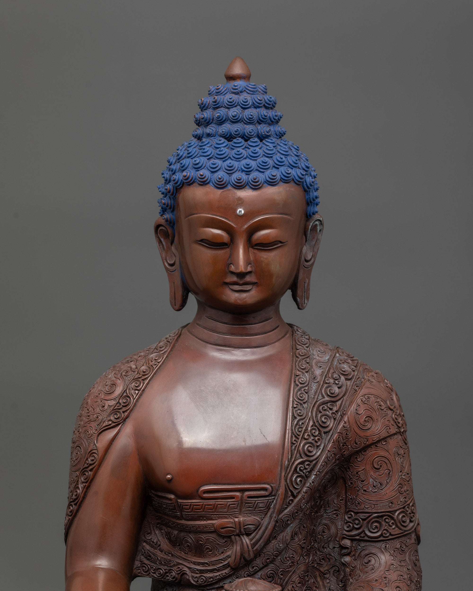Close-up of Shakyamuni Buddha’s face and finely carved Buddhist monk’s robe symbols