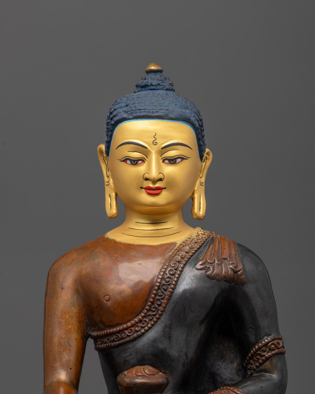 Close-up of Shakyamuni Buddha’s serene face showing gold gilding and fine lost wax detail