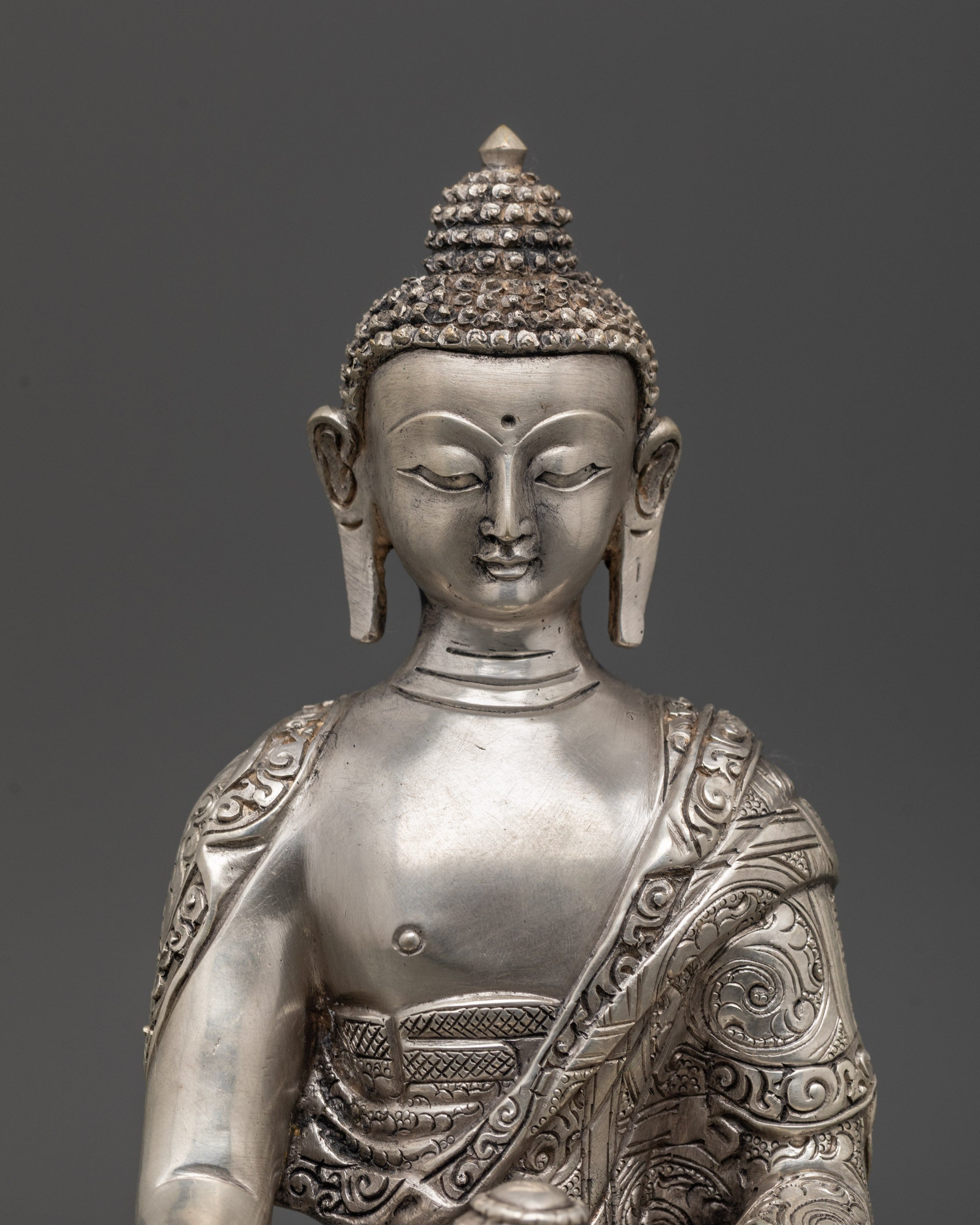 Close-up of Shakyamuni Buddha’s serene face with fine silver finish and detailed carving
