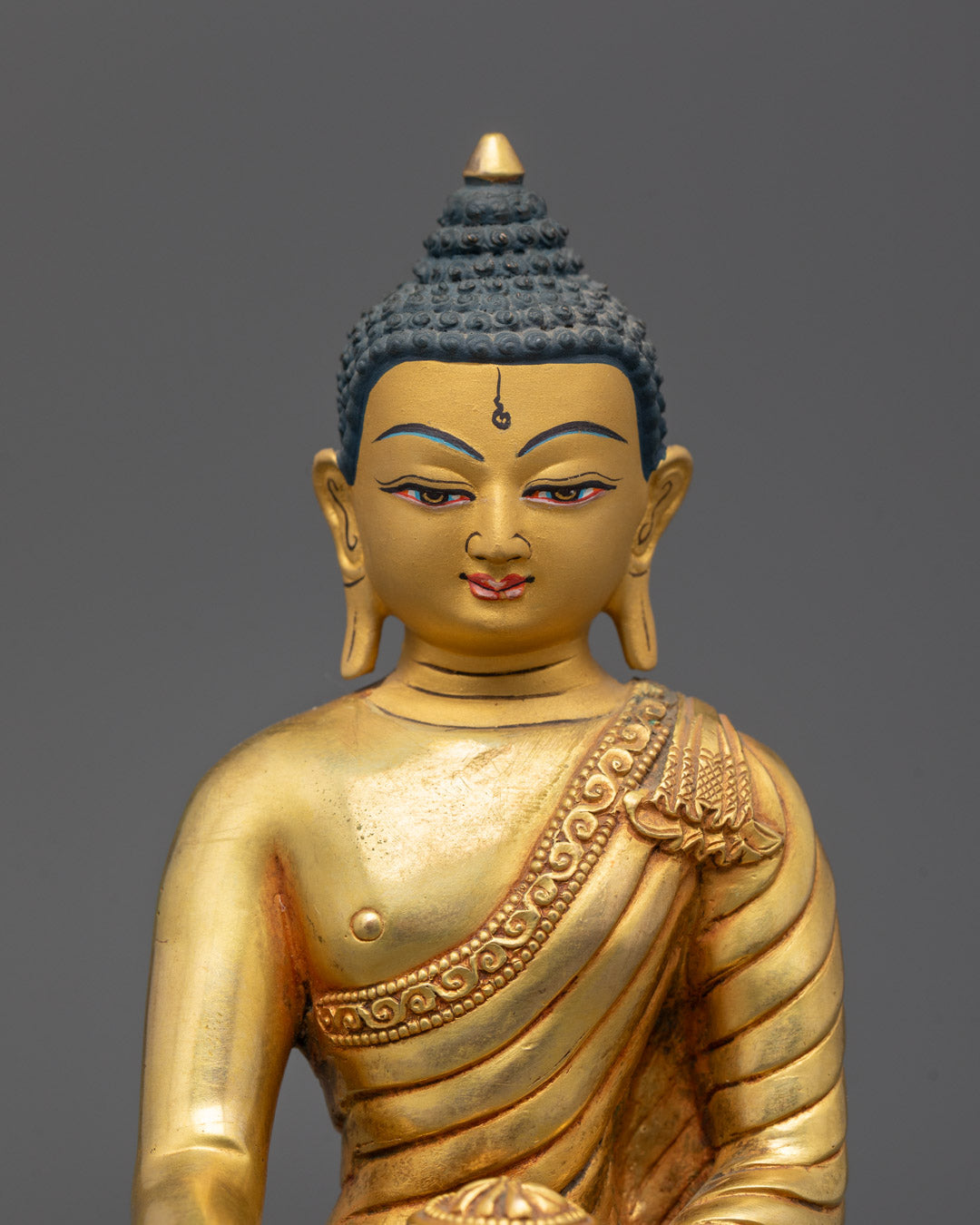 Close-up of Shakyamuni Buddha’s serene face with intricate fire-gilded gold detailing