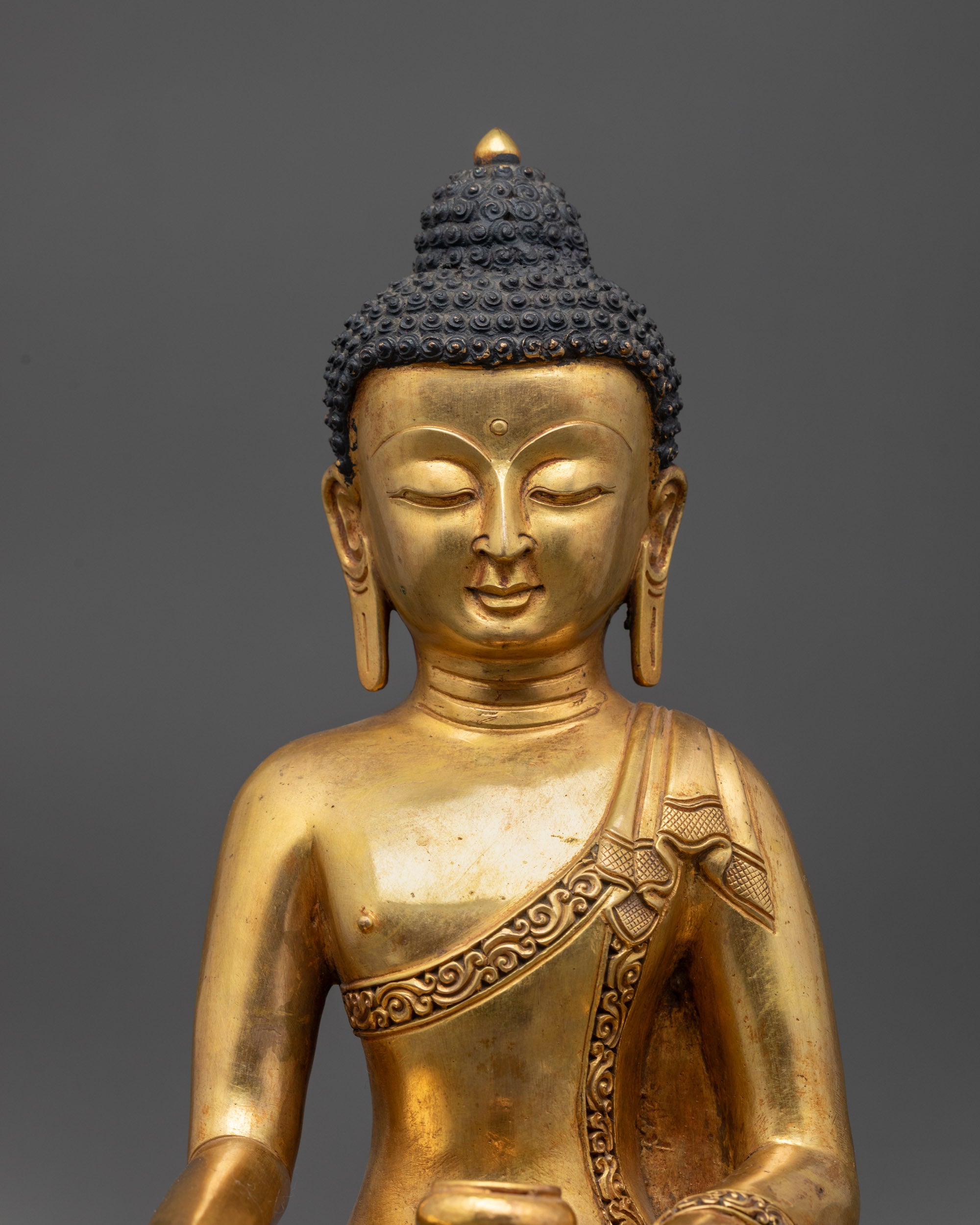 Close-up of Shakyamuni Buddha's serene face with intricate fire-gilded gold detailing