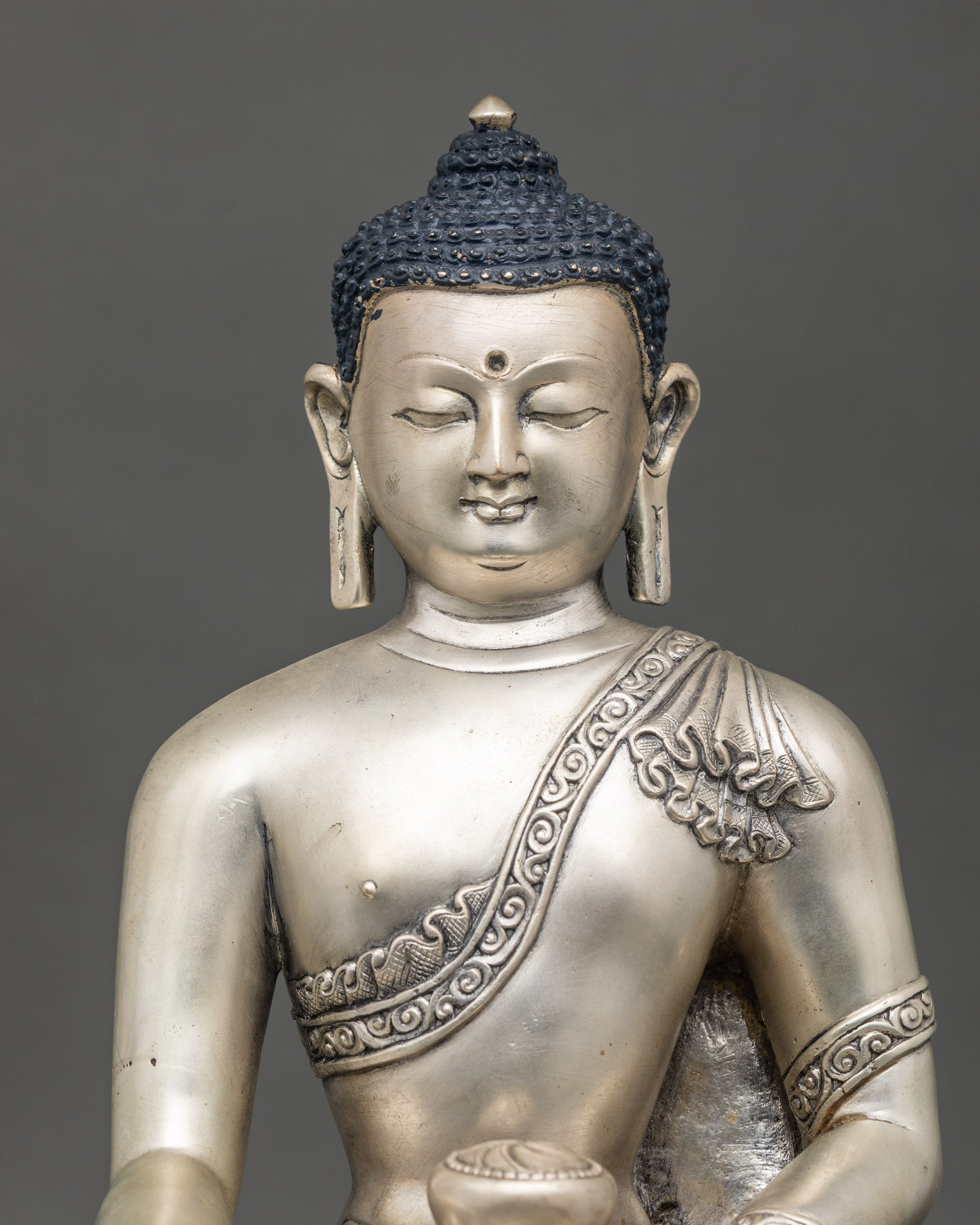 Close-up of Shakyamuni Buddha sculpture showing intricate lost-wax artisan details