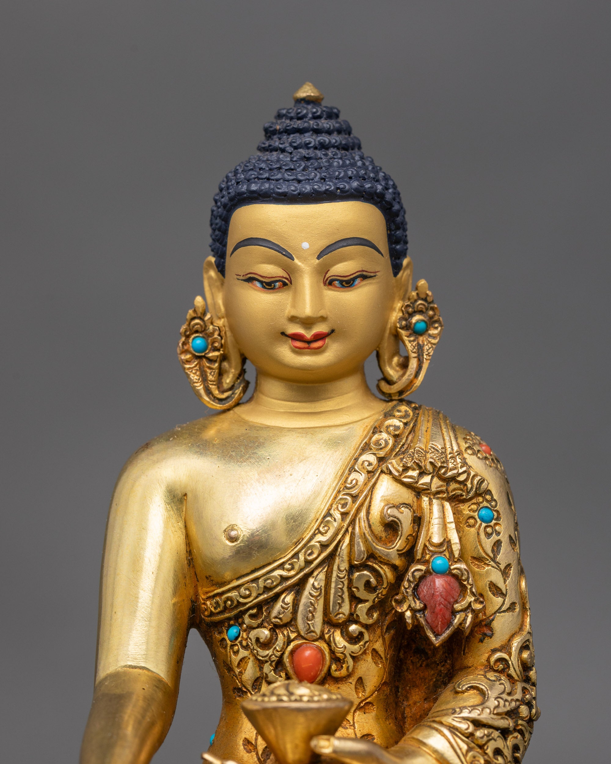 Close-up of Shakyamuni Buddha statue showing gold face and jeweled details