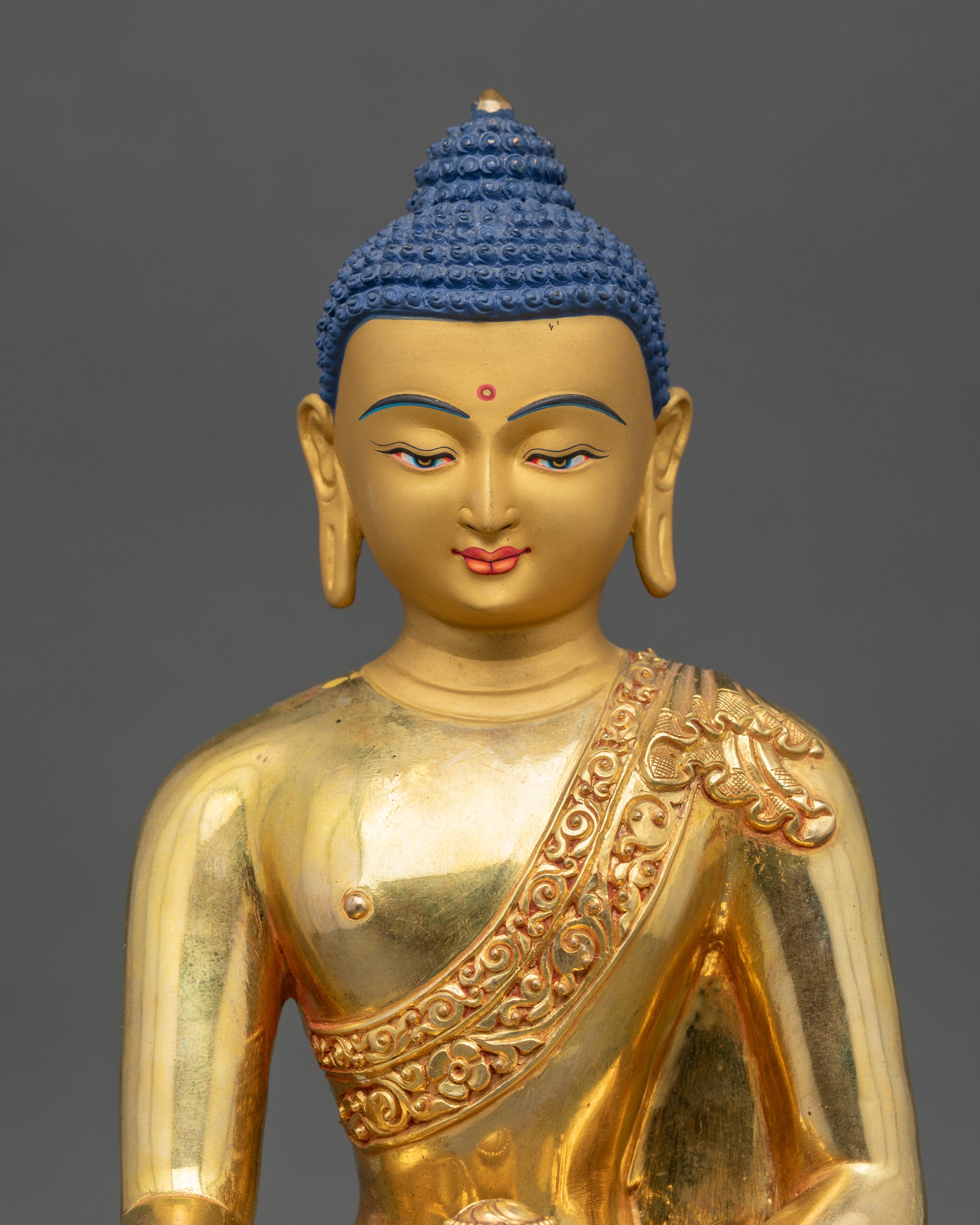 Close-up of Shakyamuni Buddha statue showing gold gilding and intricate robe details