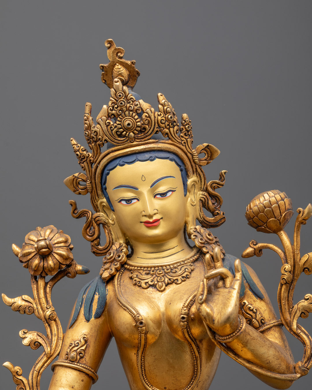 Close-up of Tara Devi’s gold-gilded face and uptala flower in hand