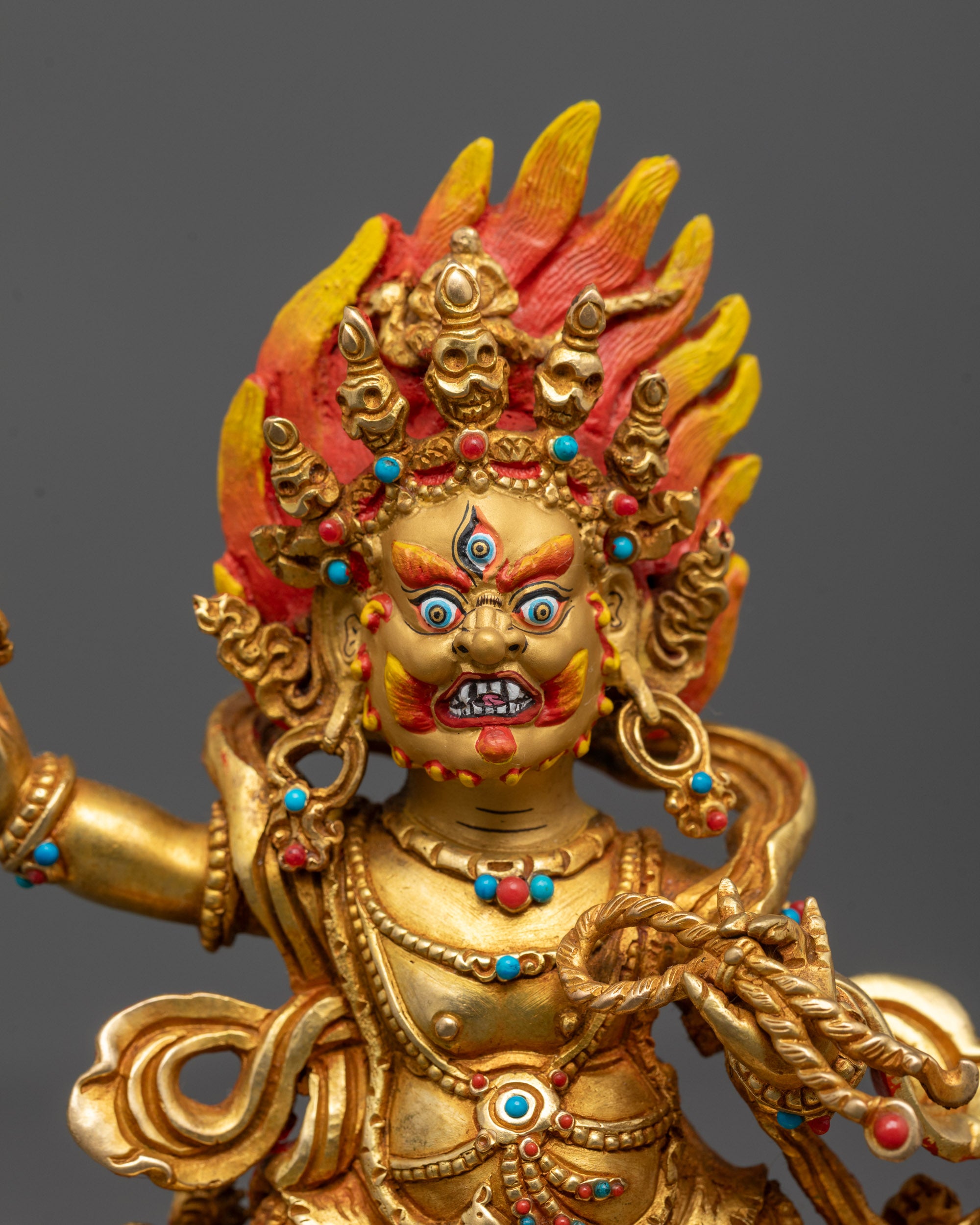 Close-up of Vajrapani holding vajra with intricate flame halo behind