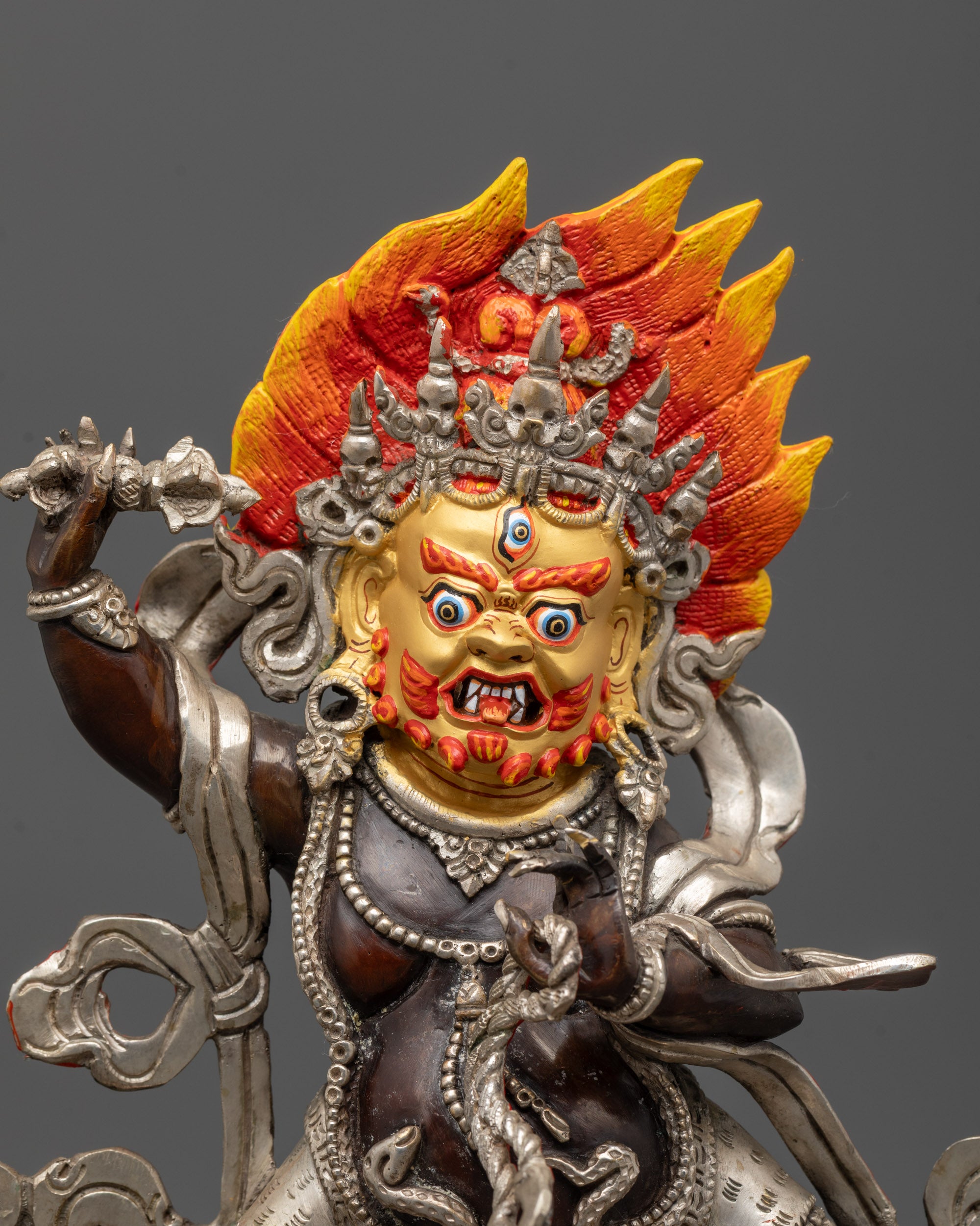 Close-up of Vajrapani statue showing wrathful face, five-skull crown and serpent details
